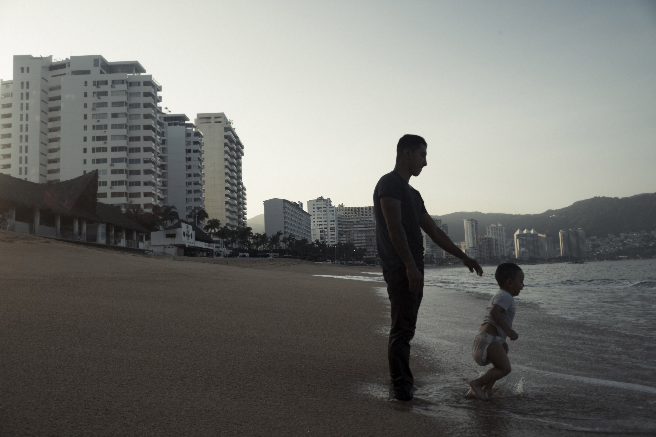 Andres Vladimir, who was visiting Acapulco from Mexico City, introduces his 3-year-old son Harek to the sea. &nbsp;Many of those visiting Acapulco&#39;s shores, especially those with extensive tattooing that could be associated with gang affiliation like Andres, visit the shores in the early hours of the day to avoid possible confrontations which could arise at other times. &nbsp;A safer time, at dawn Andres didn&#39;t have to worry as much about murder.