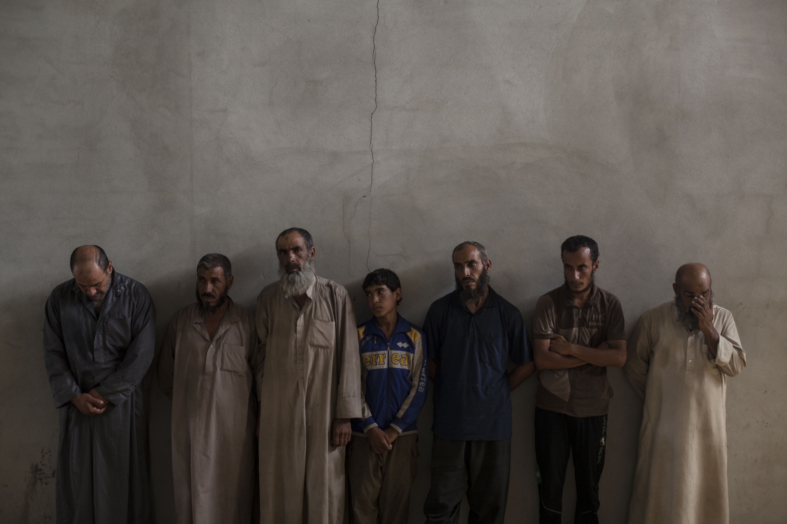 Displaced men from Hawija are lined up against a wall at a Kurdish screening center in Dibis. They are brought to the center for a screening process before being moved to camps for displaced people in the Kurdish region of Iraq.