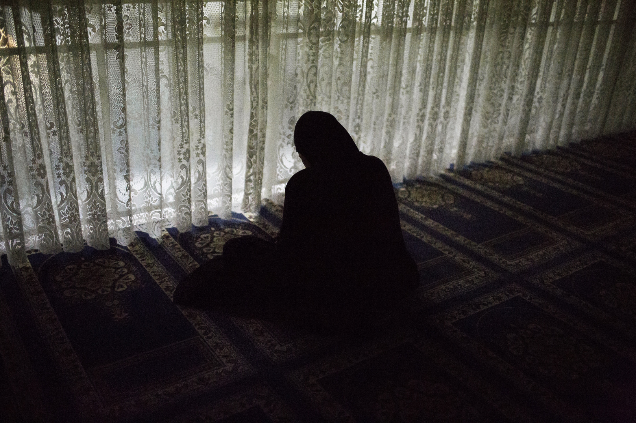 An elderly woman sits in dhikr (the remembrance of Allah through meditation and prayer) at the...