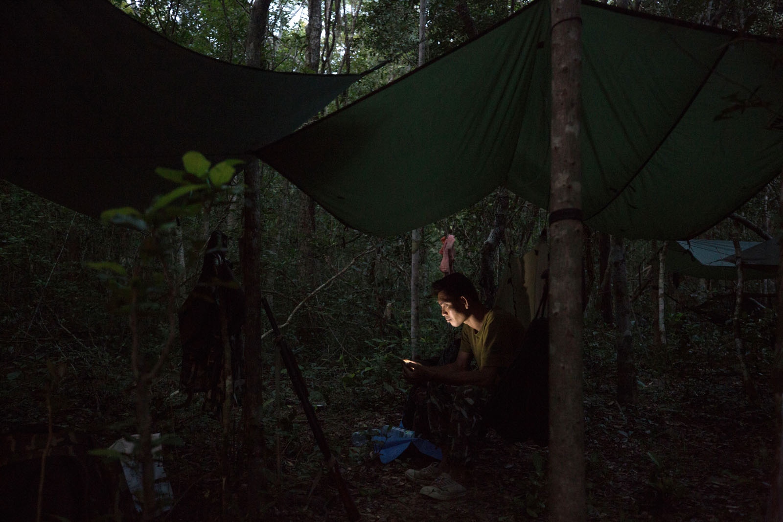 THAILAND'S FOREST RANGERS - Sompob Khamprakon, 37, rests at camp looking at photos on...