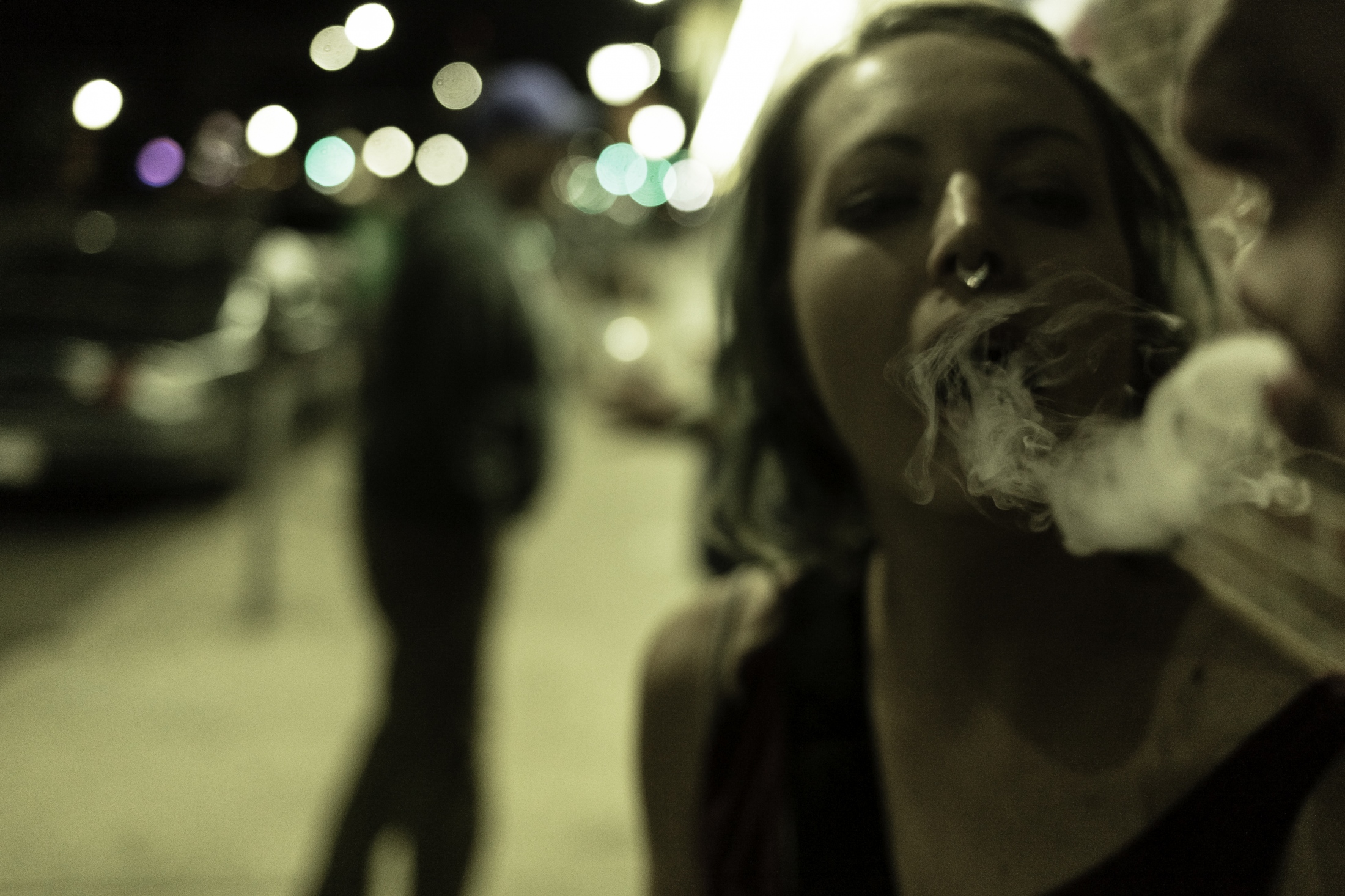 A couple of girlfriends share a marijuana joint outside of a nightclub in Colfax Av. Denver, CO....
