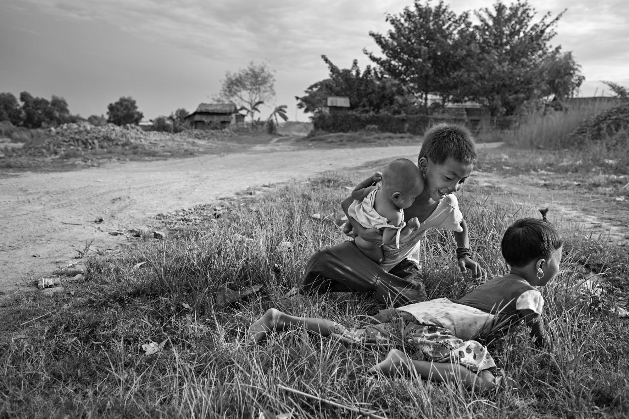Built On Their Backs -  Than Ko and Saung Ning Wai play in the grass in front of...