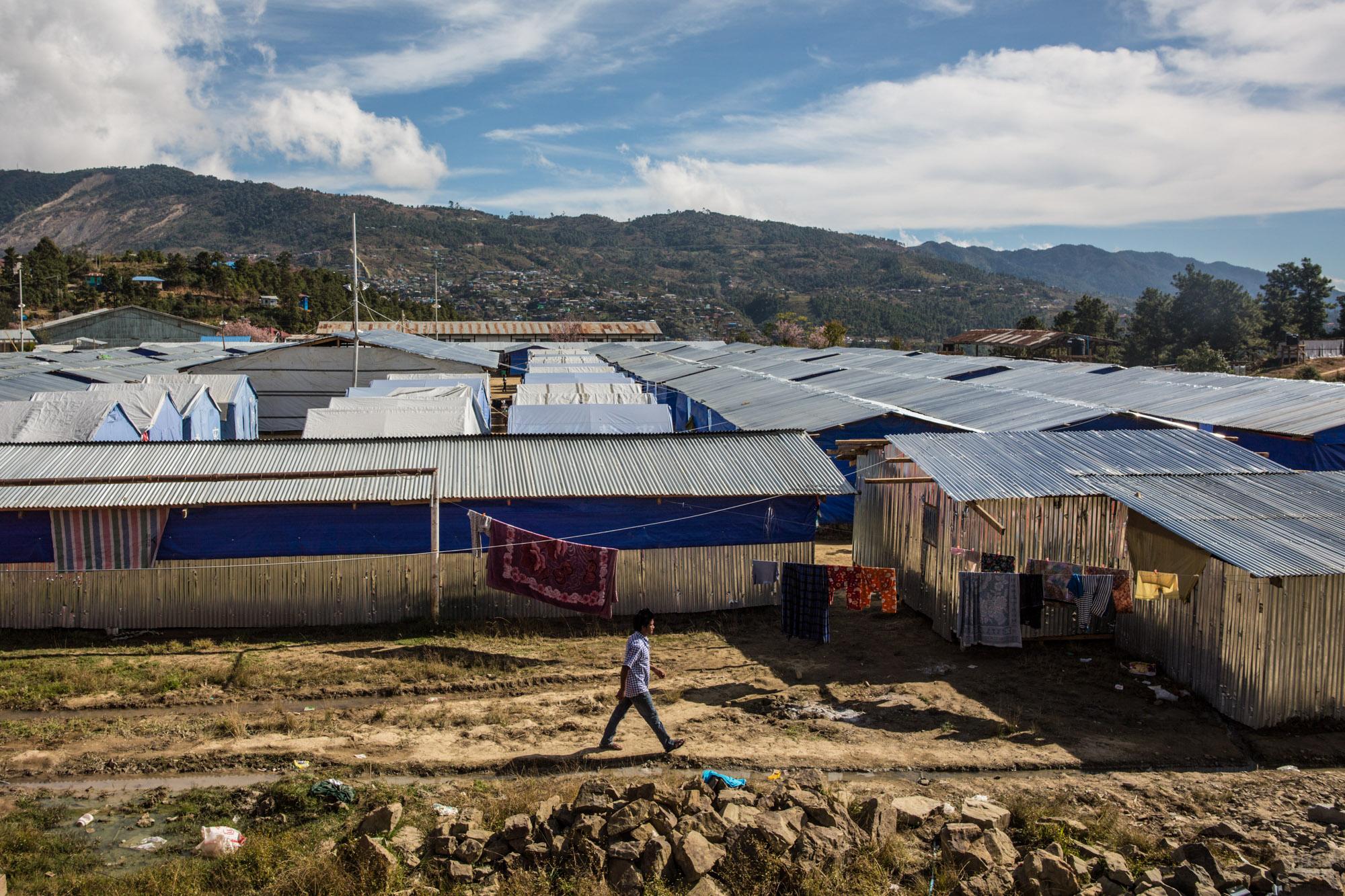 NGO - A man walks through a temporary refugee camp in Hakha,...