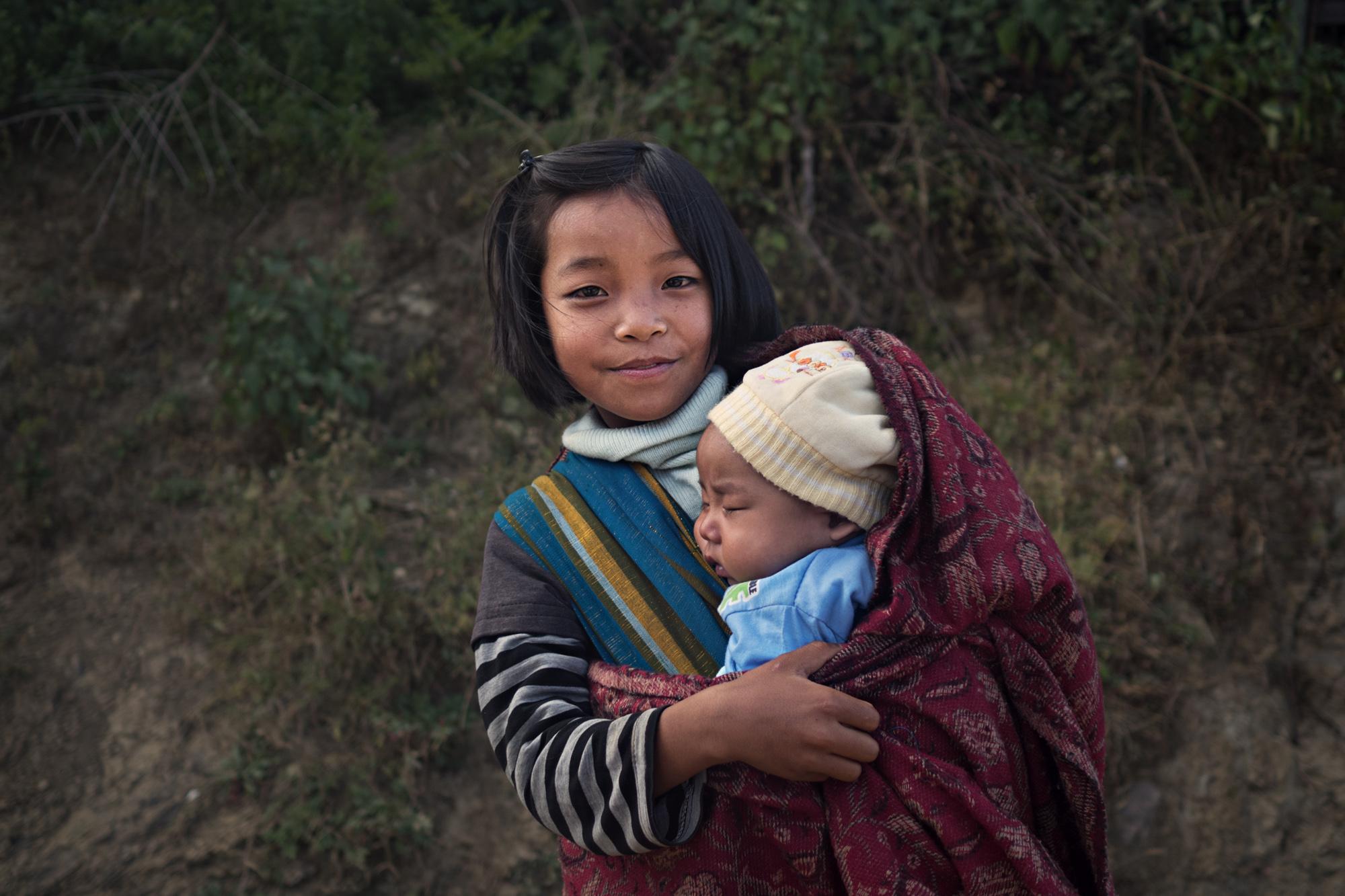 NGO - A young girl holds her baby sister for a portrait at...