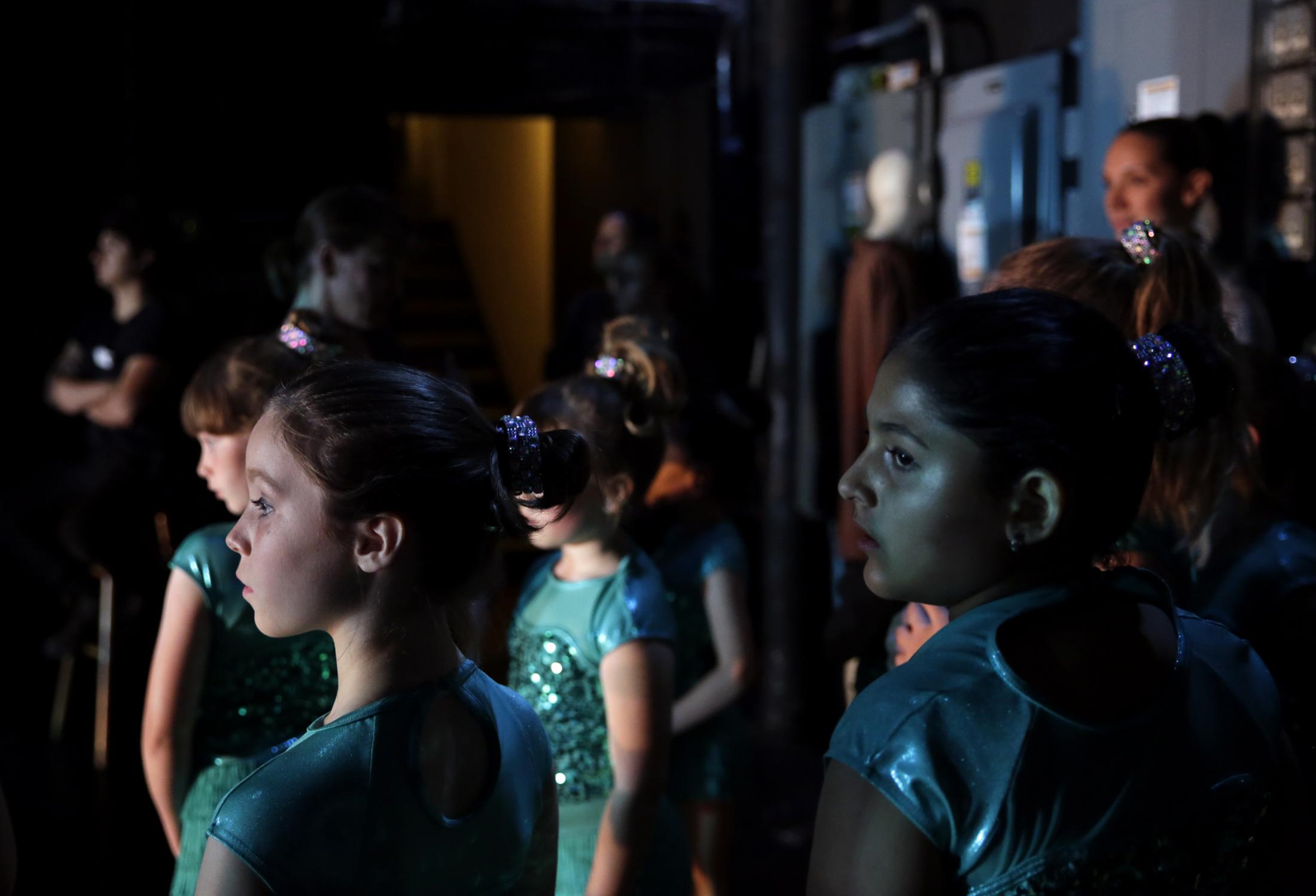 Singles - Young dancers watch the performance from backstage during...