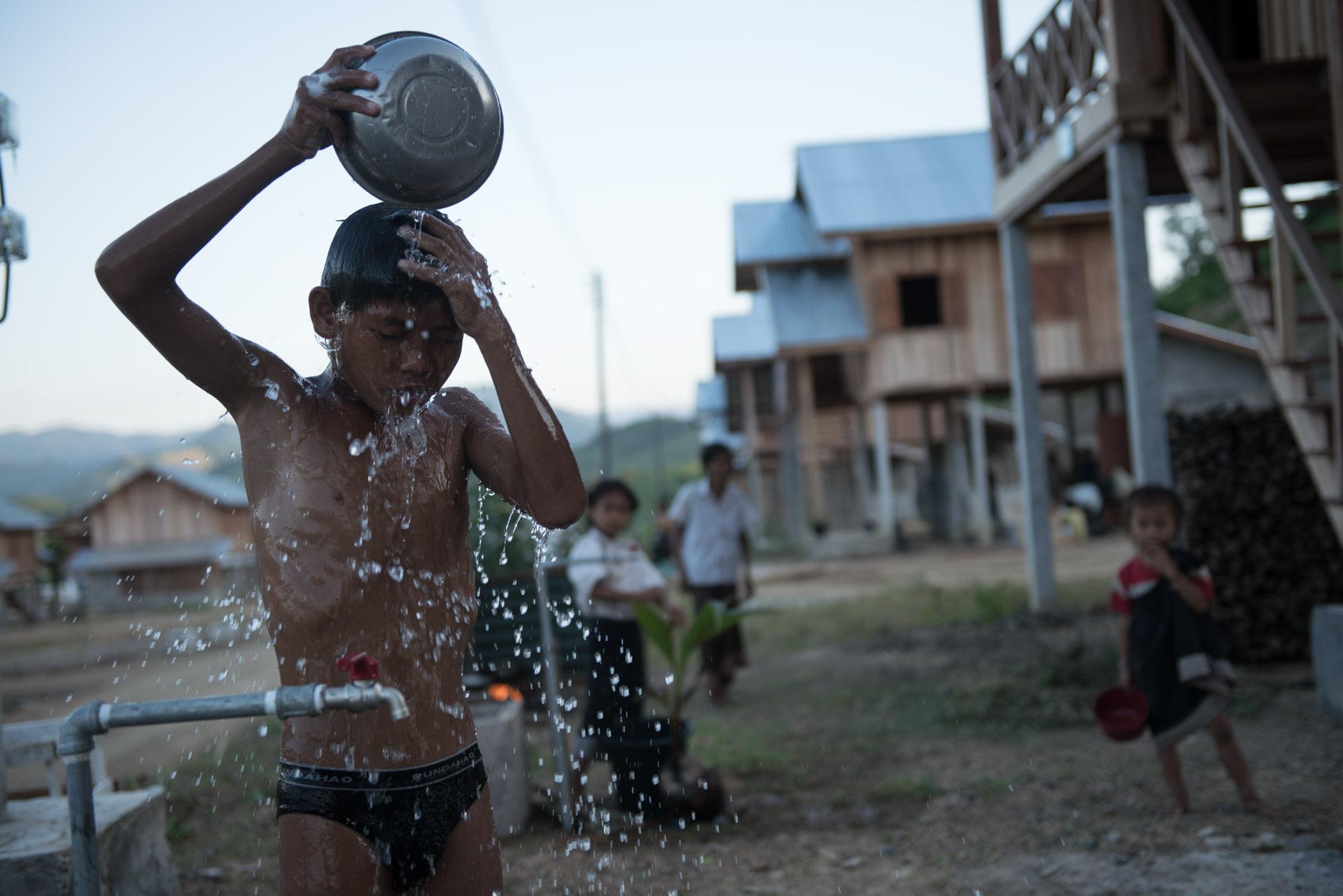 Damming The Mekong River - A young kid takes a bath after being taken to the new...