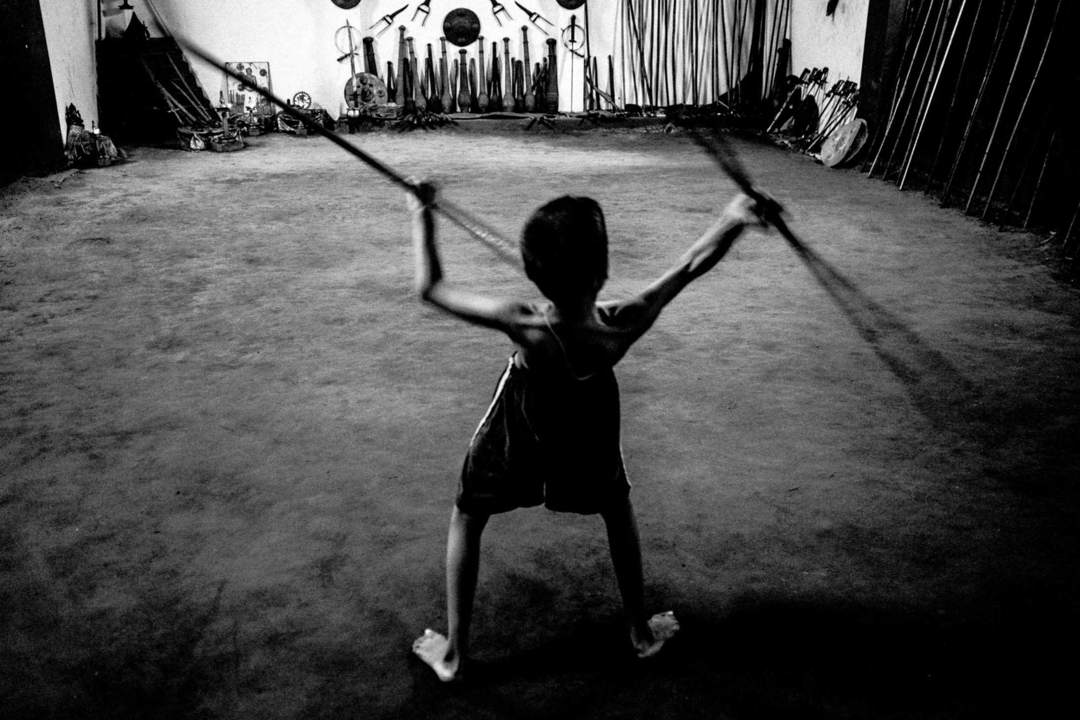  A child does coordination training with the help of two bamboo sticks while waiting for his master. 