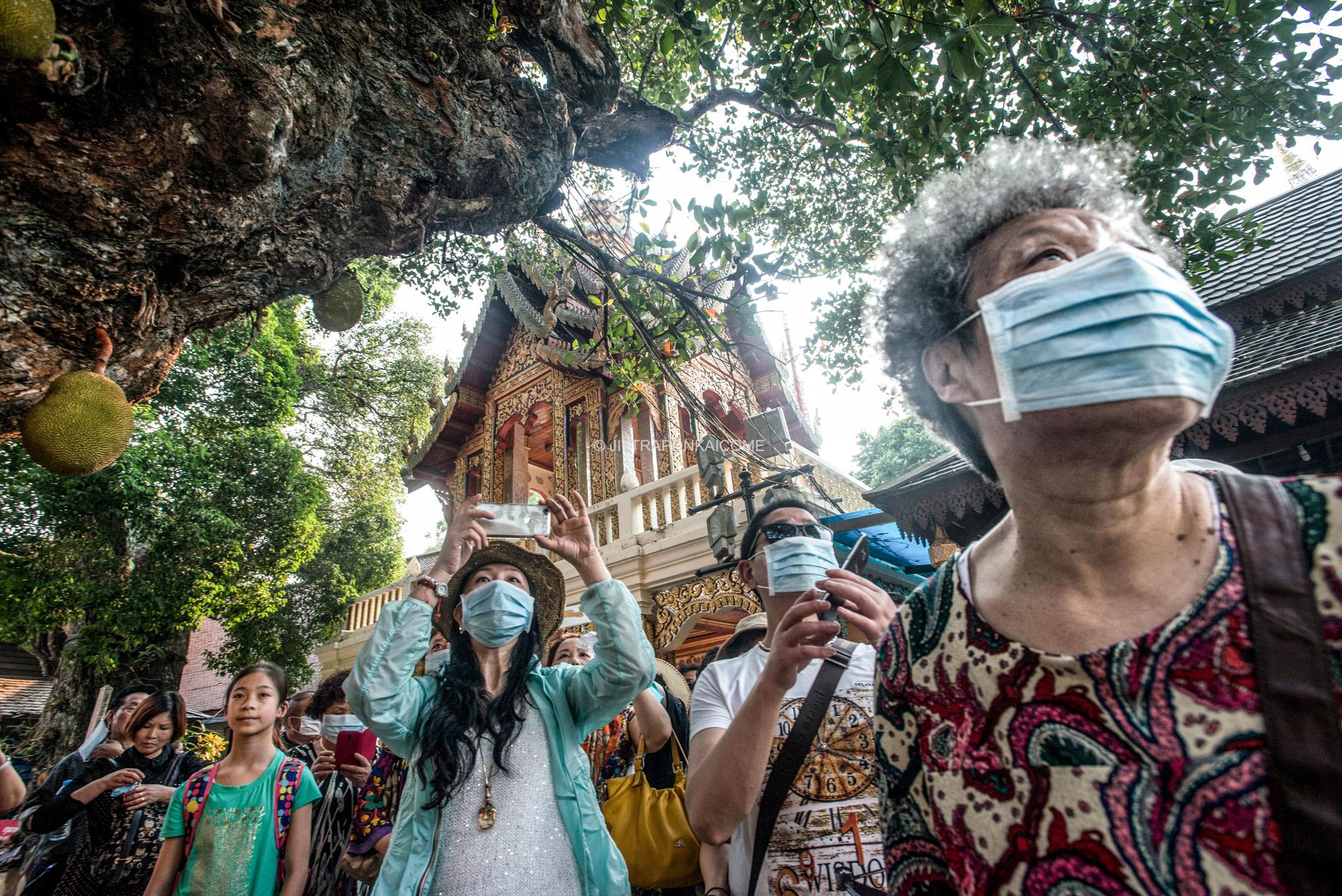 Asian tourists wear dust protection masks during making a visit to tourist destinations in the...