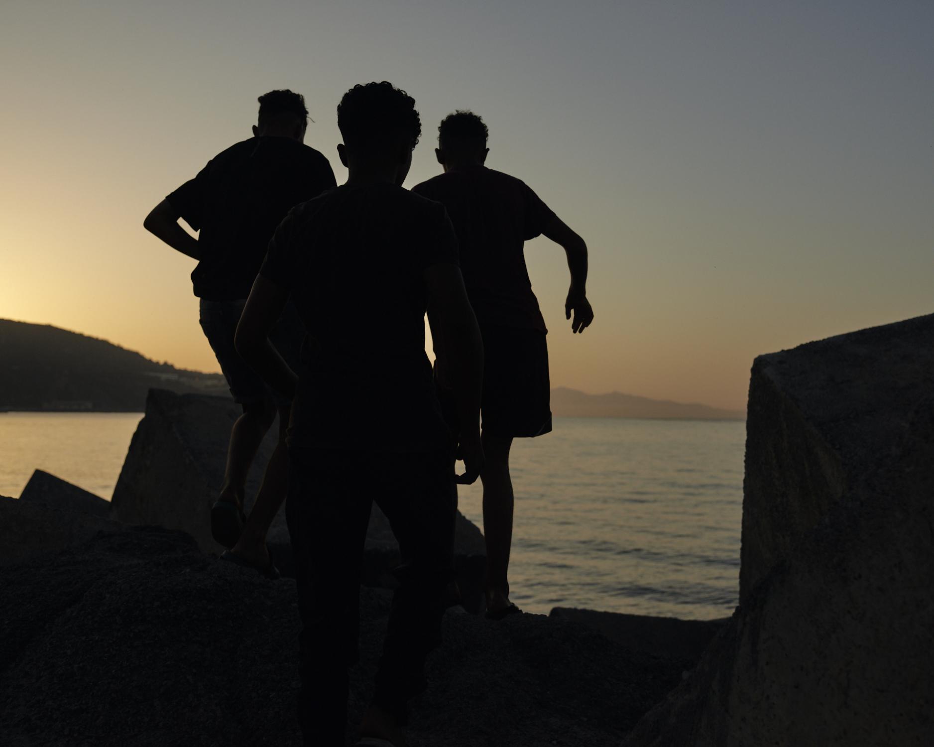  A group of kids jumps over seawall rocks nearby the boardwalk in Ceuta. Plagues, cold, and...