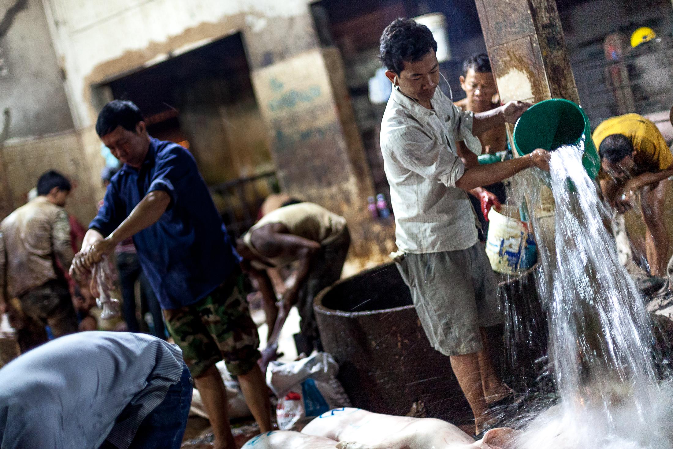 Inside a Cambodian Slaughterhouse - SIEM REAP, CAMBODIA - FEBRUARY 22: A worker throws a...