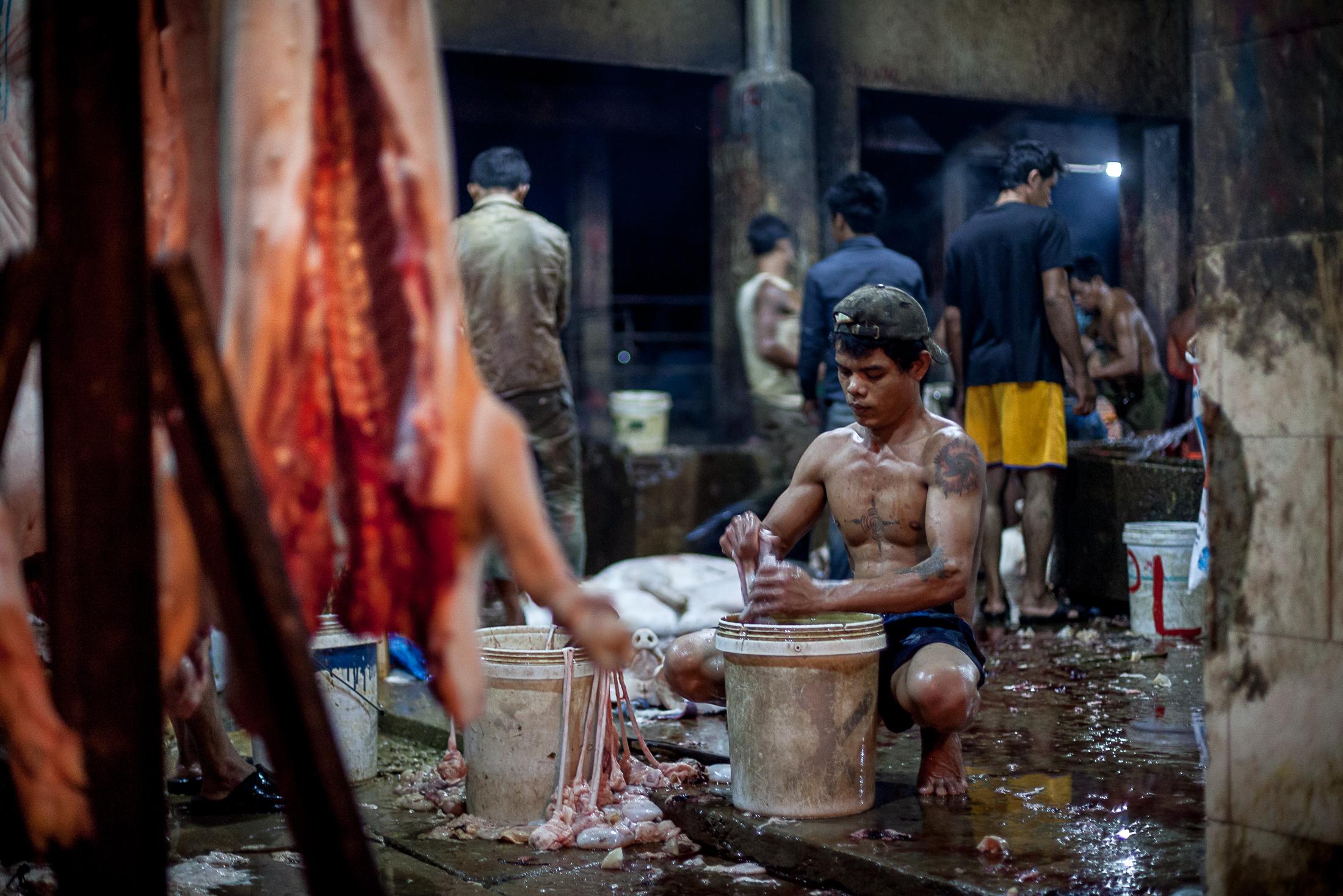 Inside a Cambodian Slaughterhouse - SIEM REAP, CAMBODIA - FEBRUARY 22: A worker cleans the...