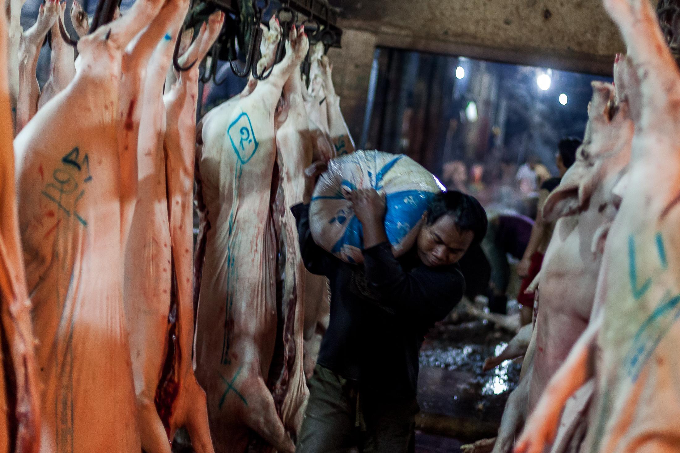 Inside a Cambodian Slaughterhouse - SIEM REAP, CAMBODIA - FEBRUARY 22: A broker carries a bag...