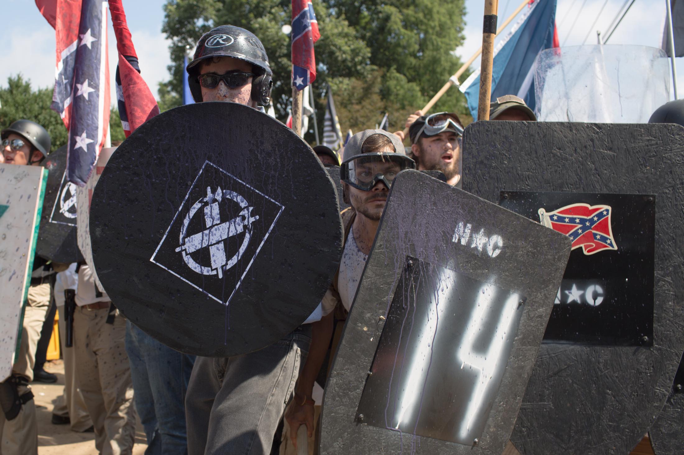 Charlottesville - White supremacist protesters raise their shields as...