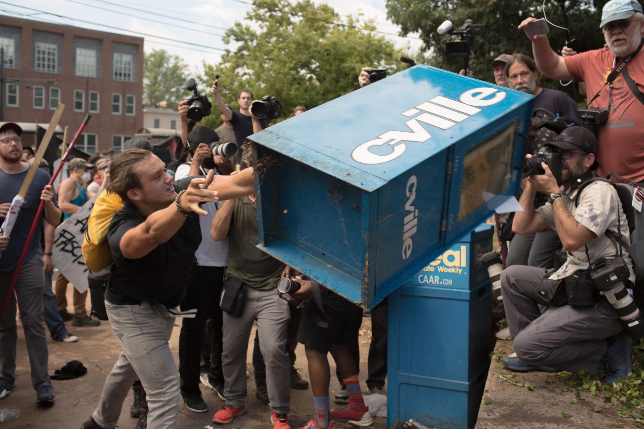 Charlottesville - An anti-fascist protester throws a newspaper box at white...