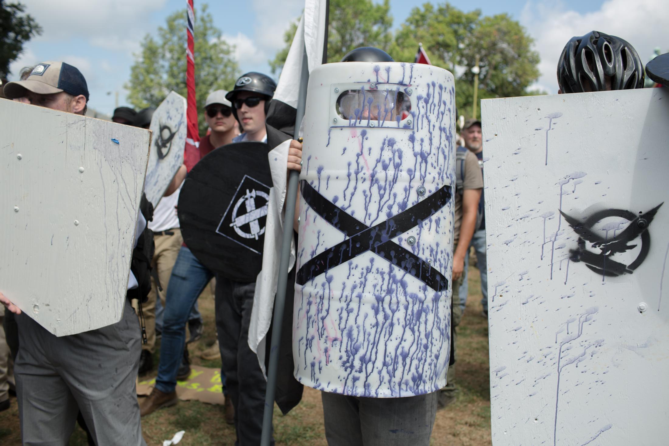 Charlottesville - White supremacists hold up shields covered in purple...