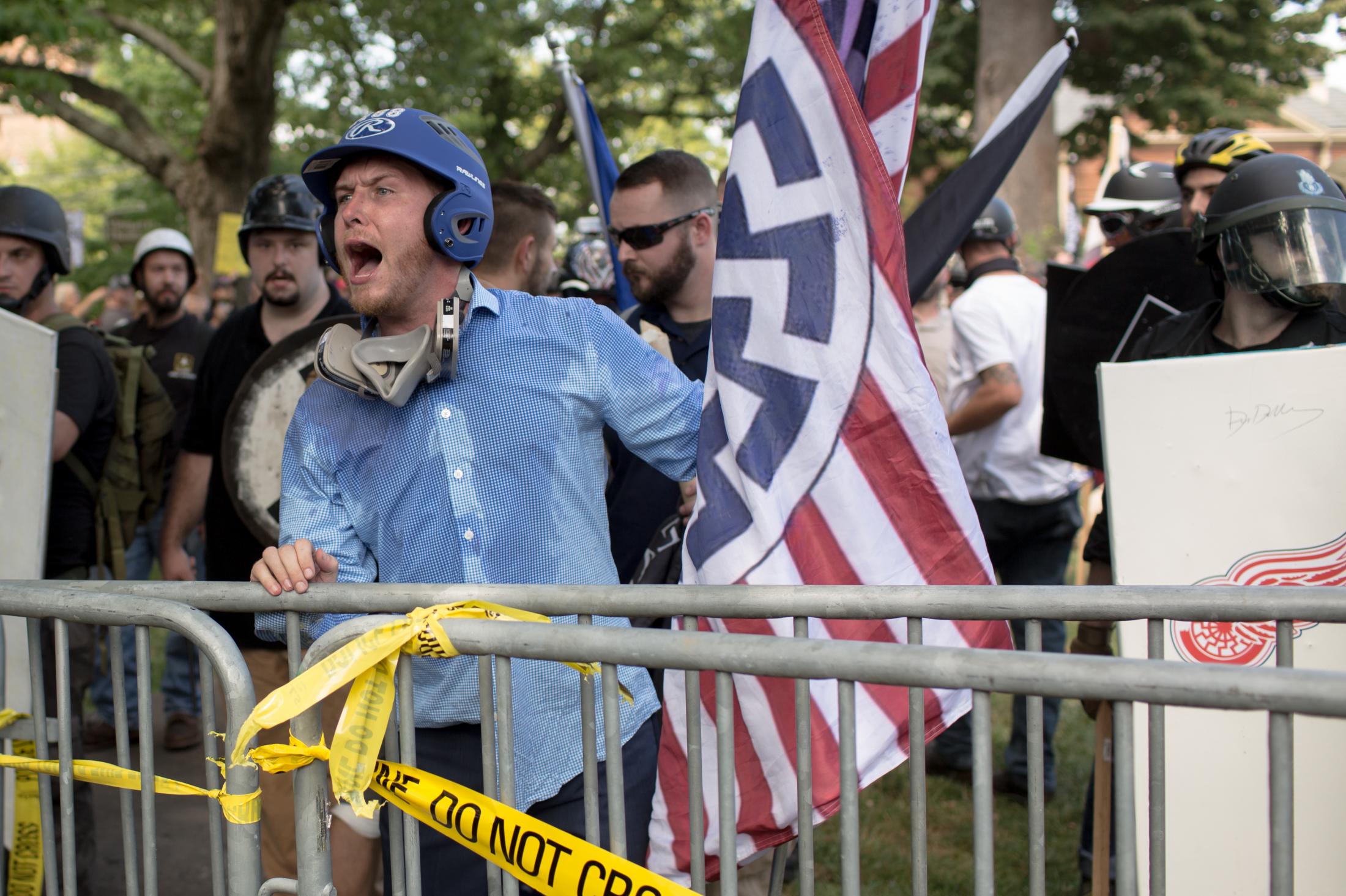 Charlottesville - A white supremacists protester holding a flag with a...