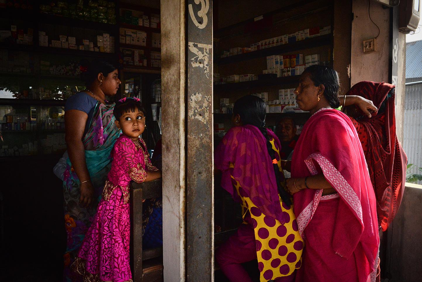 Women with their children buy steroids at a pharmacy just outside of Daulatadia Brothel in...