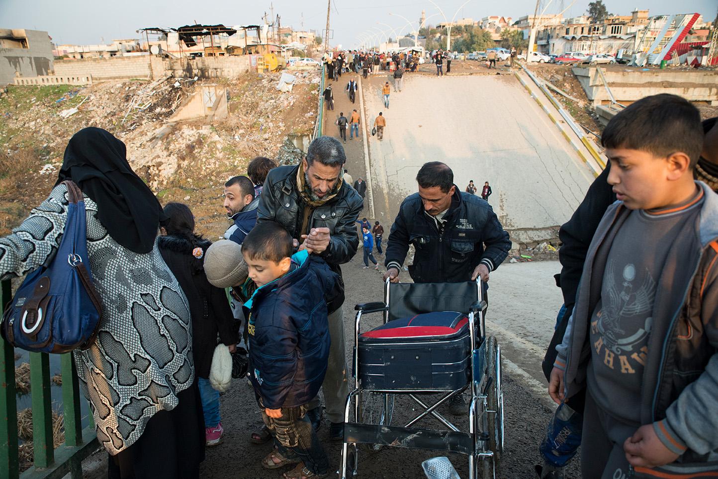 Mosul, Iraq. Civilians pass over a collapesed bridge in the market place of the recently...