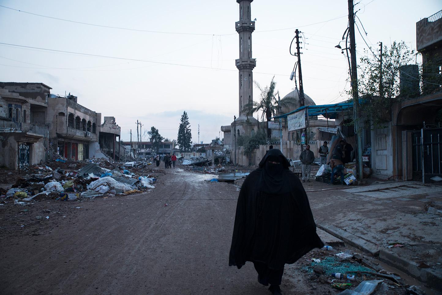 Mosul, Iraq. A woman walks past a mosque destroyed by ISIS in the Al Sukar neighborhood of...