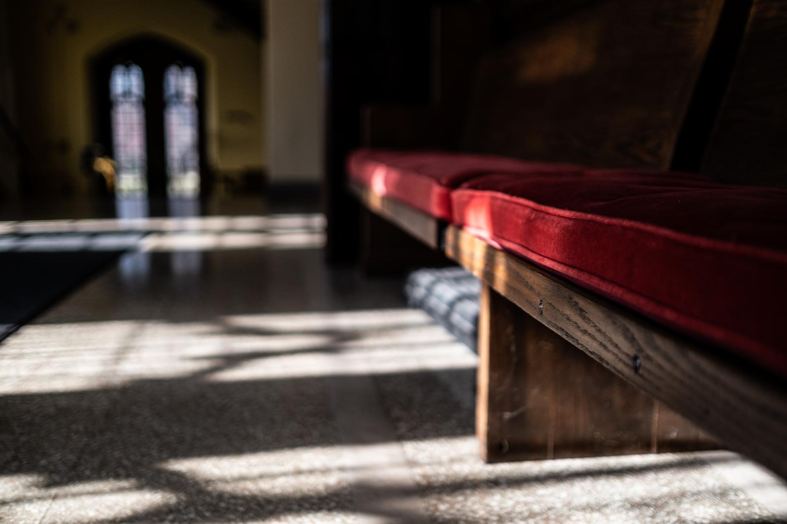 The Church - Light casts on a pew which has the same red velvet as the...