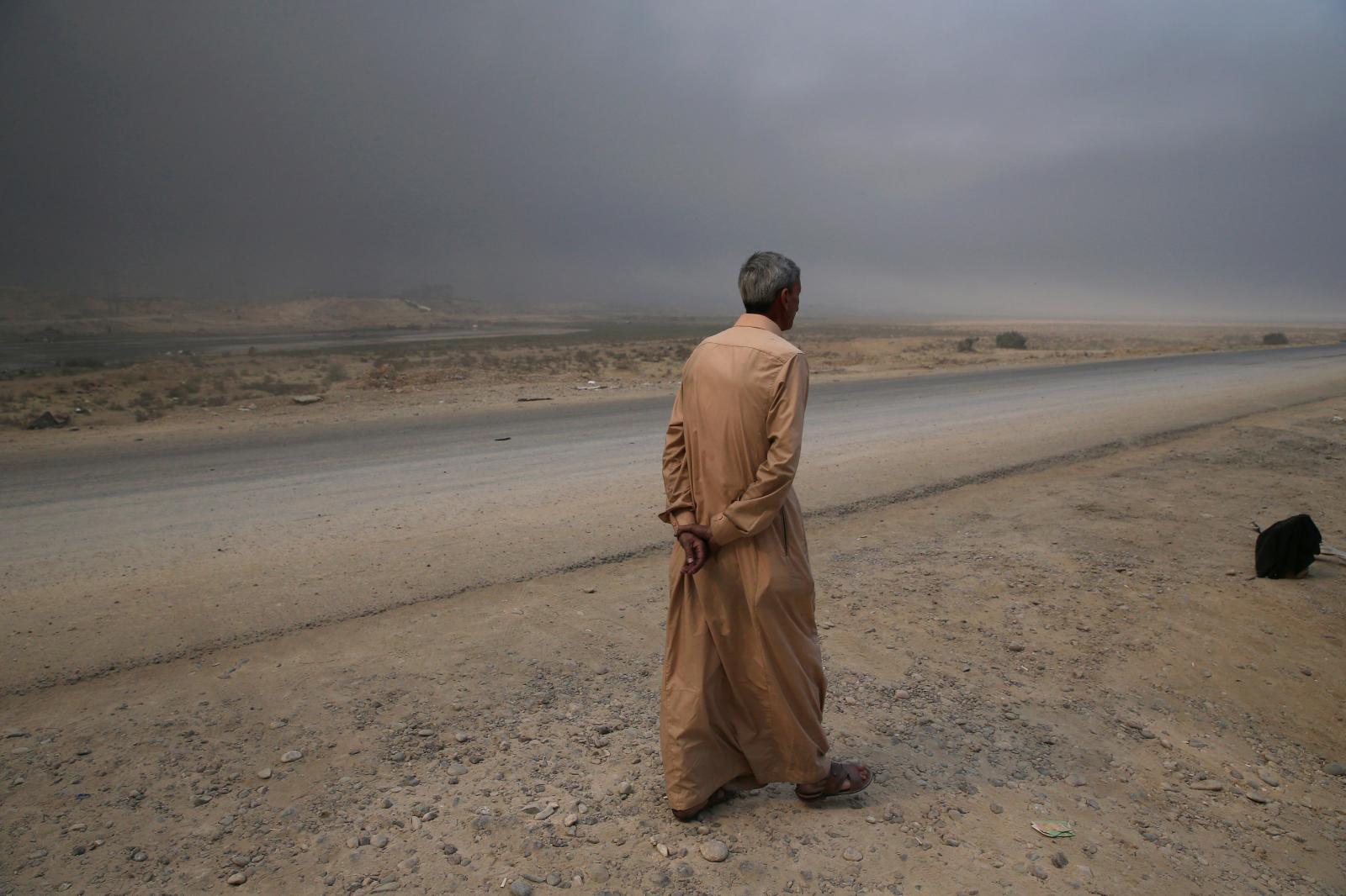 SINGLES - A man walks down a road in Qayyarah, some 50 kilometers...