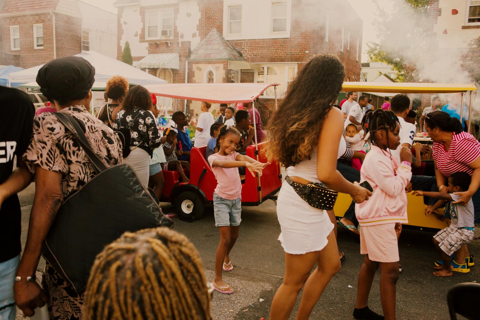 Malaysia Smith, 7, reaches out to her mom after getting off the trackless train from OnTimeEntertainment during the block party in Laurelton neighborhood in Queens, New York hosted by Sudan Deane.