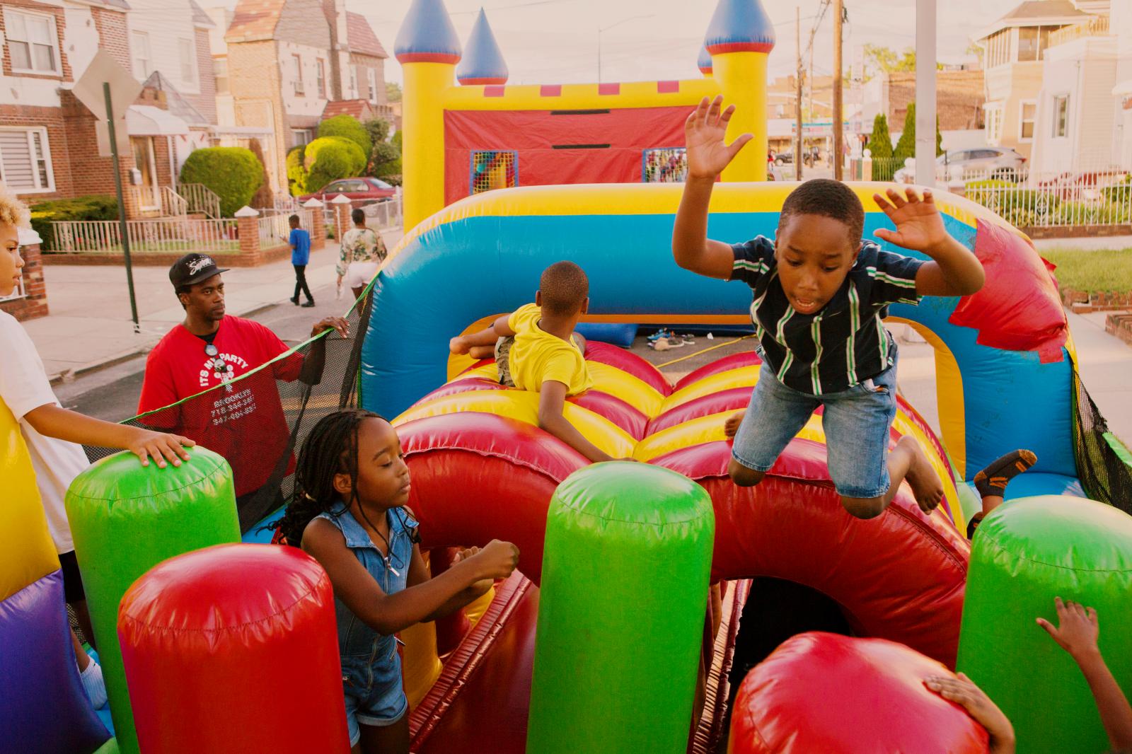 Benjamin Burton, 7, plays with inflatable obstacle course from ItsMyParty NYC during the block party in Laurelton neighborhood in Queens, New York hosted by Sudan Deane.