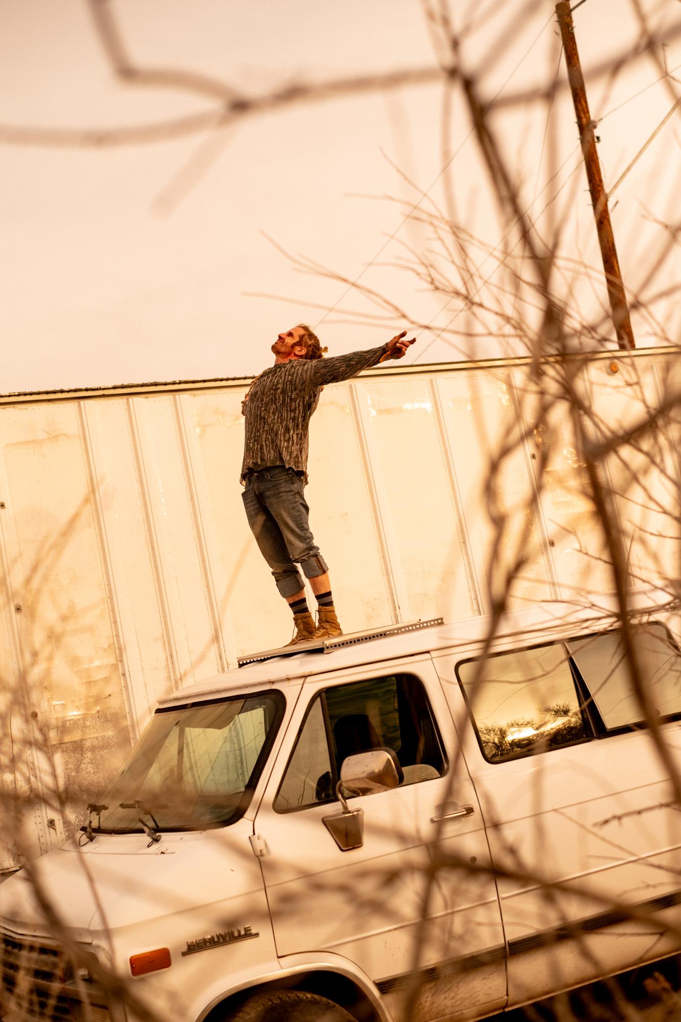 A Warm Winter (An Ongoing Journey) - Brad standing on his van's roof. Quartzsite, Arizona.