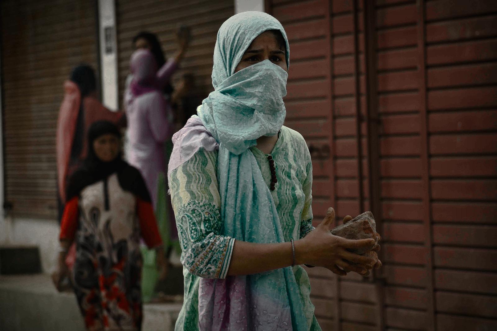 Kashmir-The Never Ending War - A Kashmiri woman protester gathers stones to pelt at...