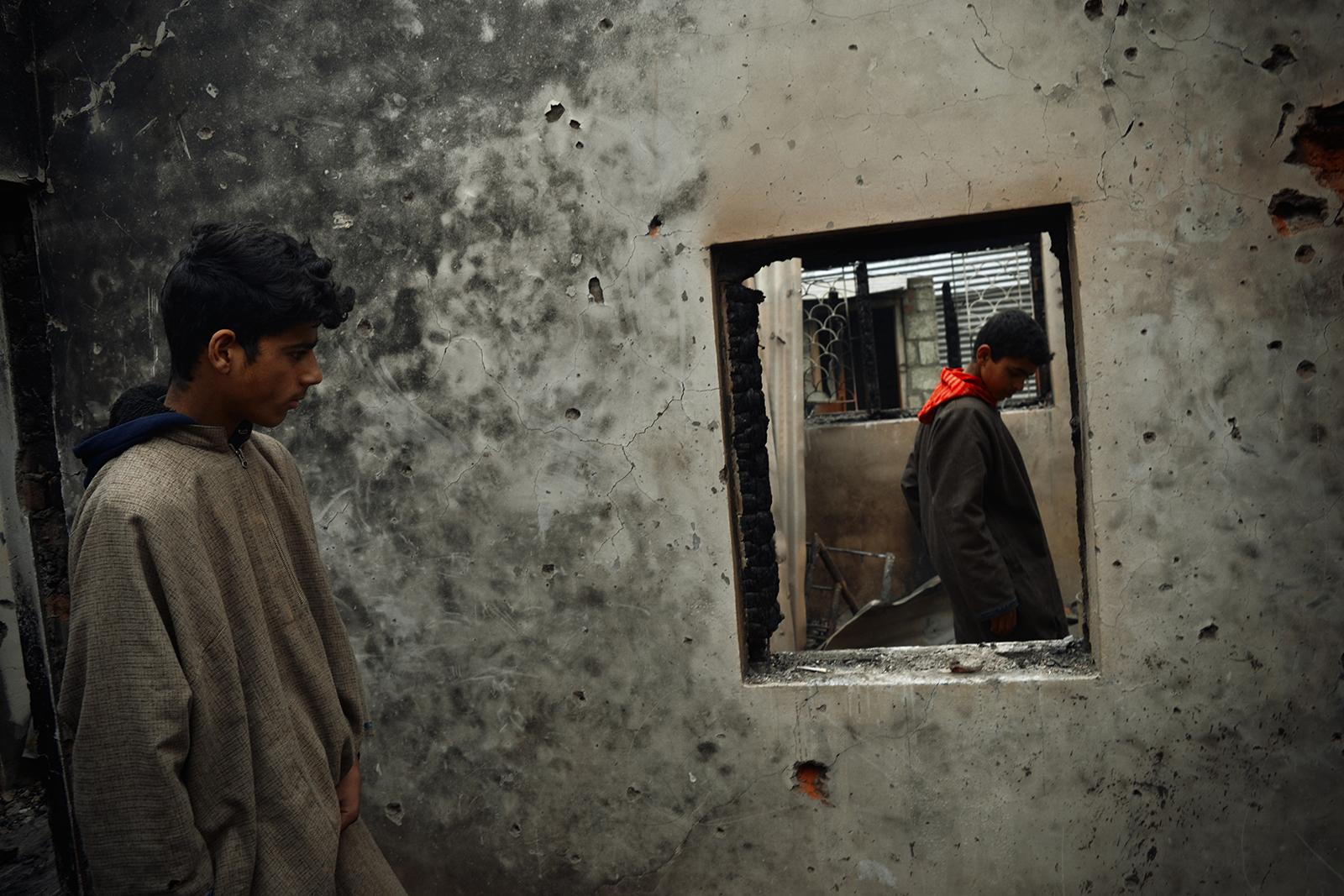 Kashmir-The Never Ending War - Young boys inspect a damaged house that was raised to...