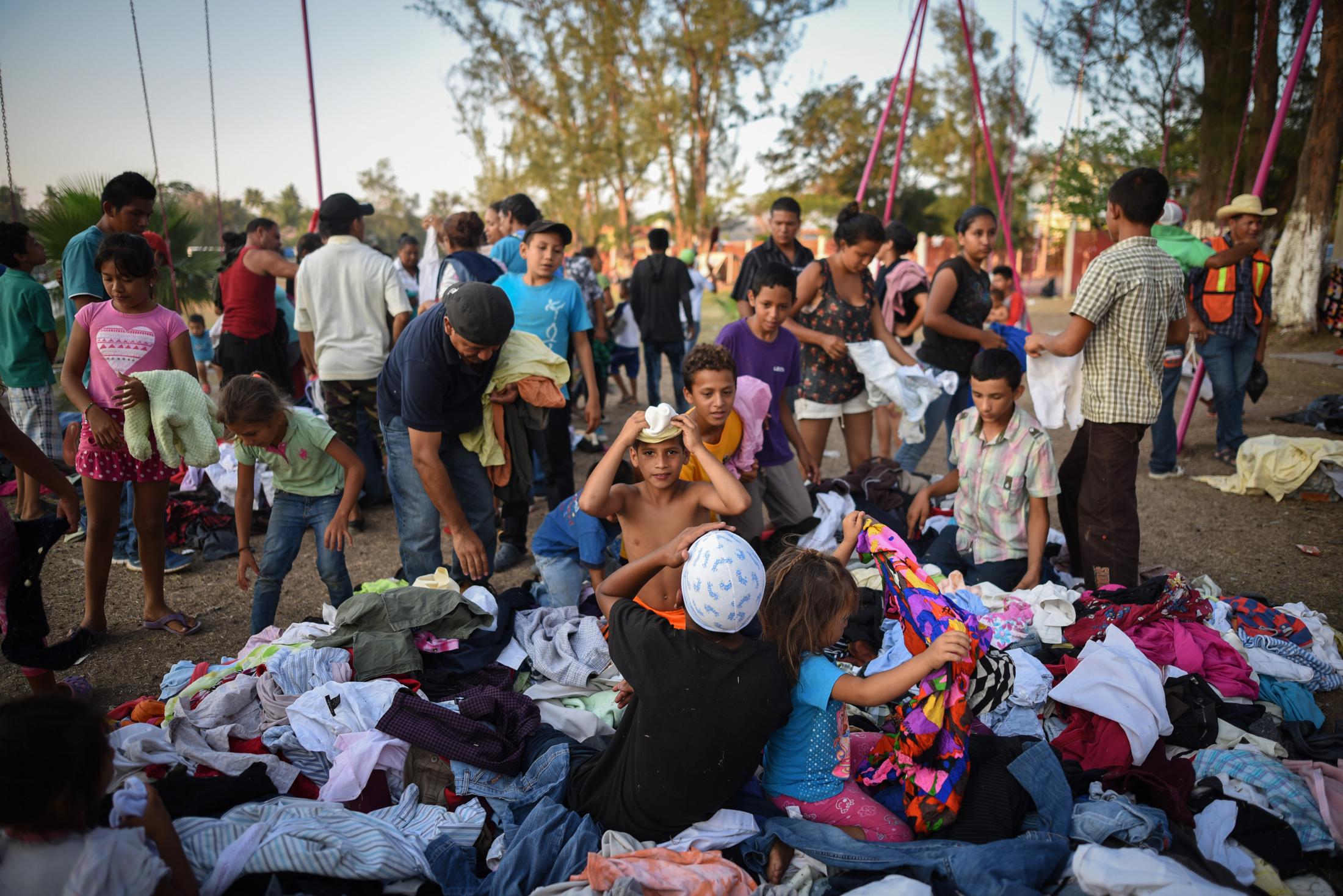 Migrantes centroamericanos escogen ropa que fue donada para ellos en un centro deportivo donde se...