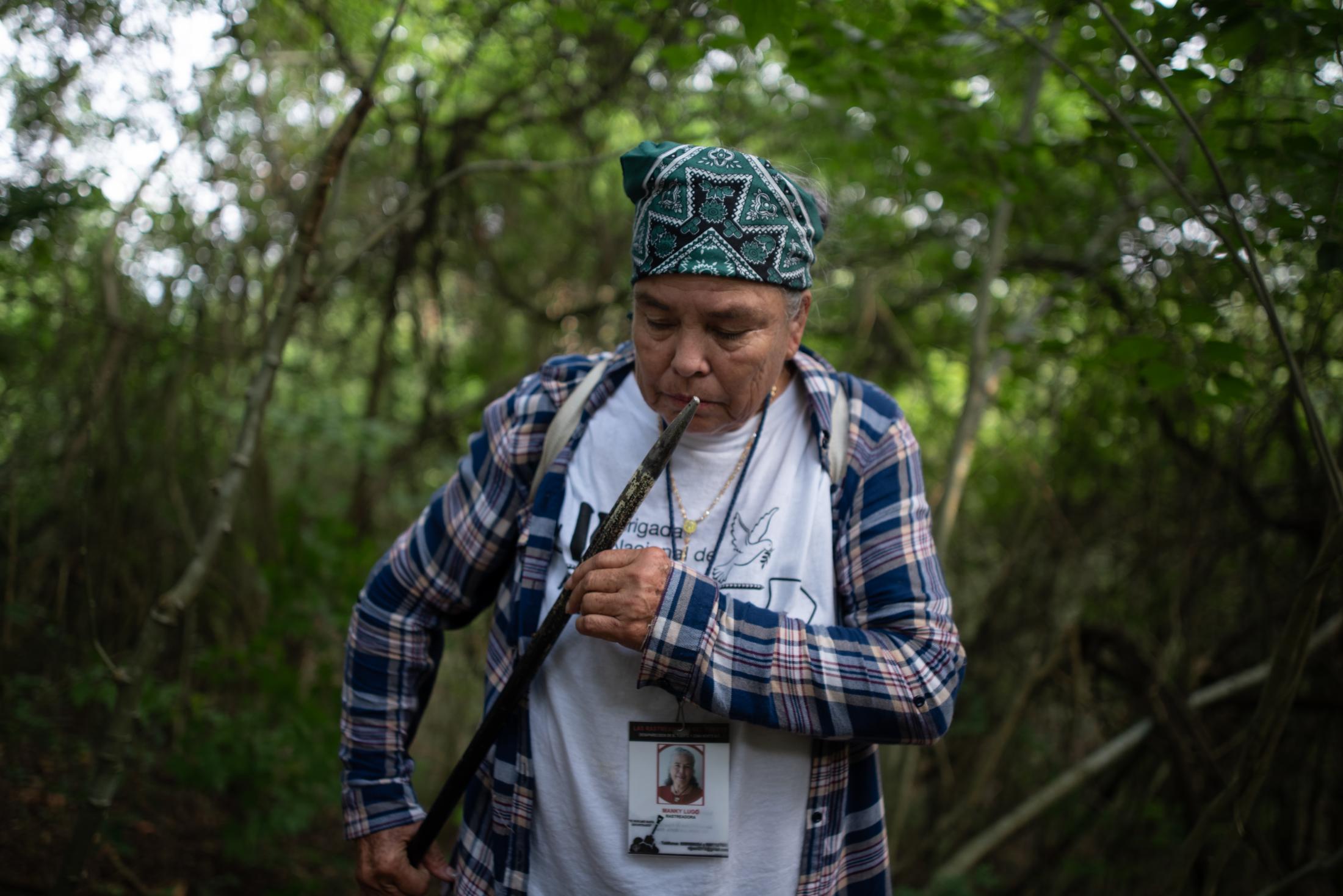 Manky Lugo, 64, seeker for missing persons of Sinaloa, Mexico, smells a metallic tool that buried in the earth in field that is investigated by police authorities and family groups participating in the fifth National Missing Persons Search Brigade in Tihuatlan, Veracruz, Mexico, on February 20, 2020. Victoria Razo for NPR