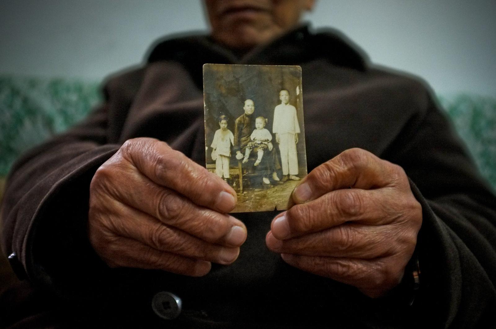 Cao holds the only photograph of himself, his mother and two siblings, taken only two weeks...