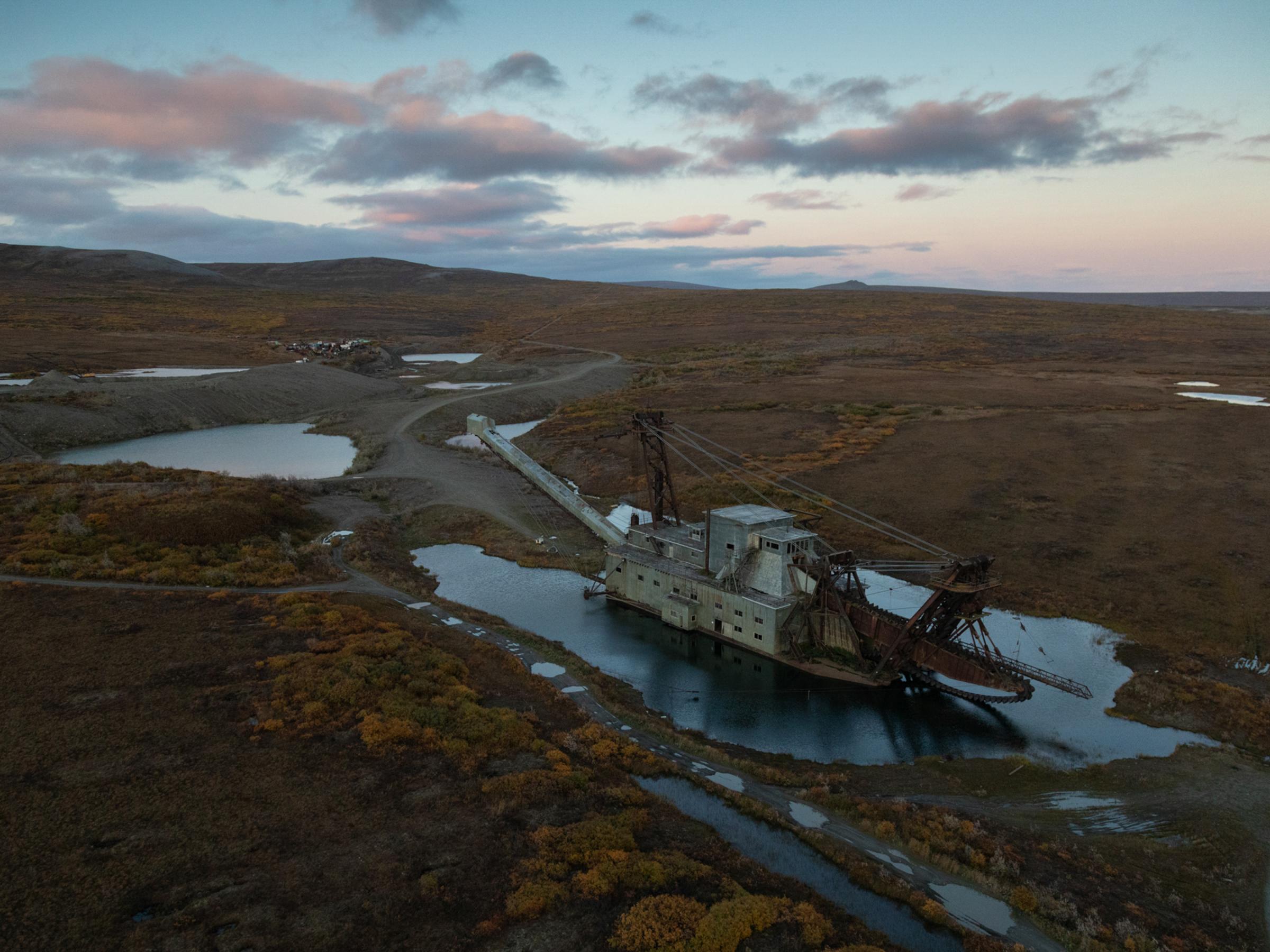 Polar Paradox - An abandoned gold dredger sits in the tundra behind Nome,...