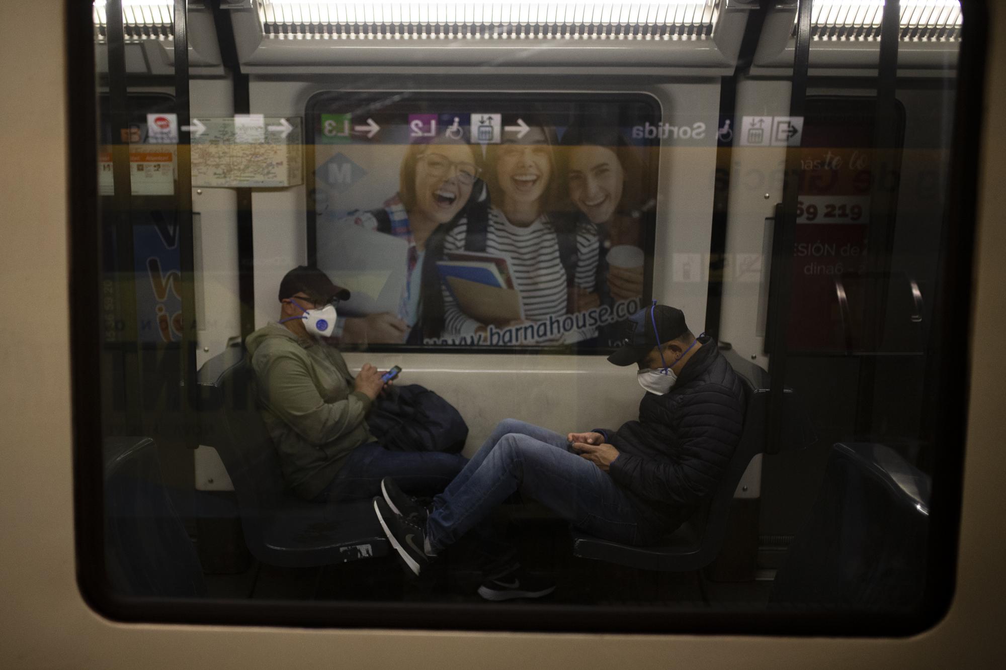 Covid 19 Daily News - Two passenger wearing protective masks sit inside a train...