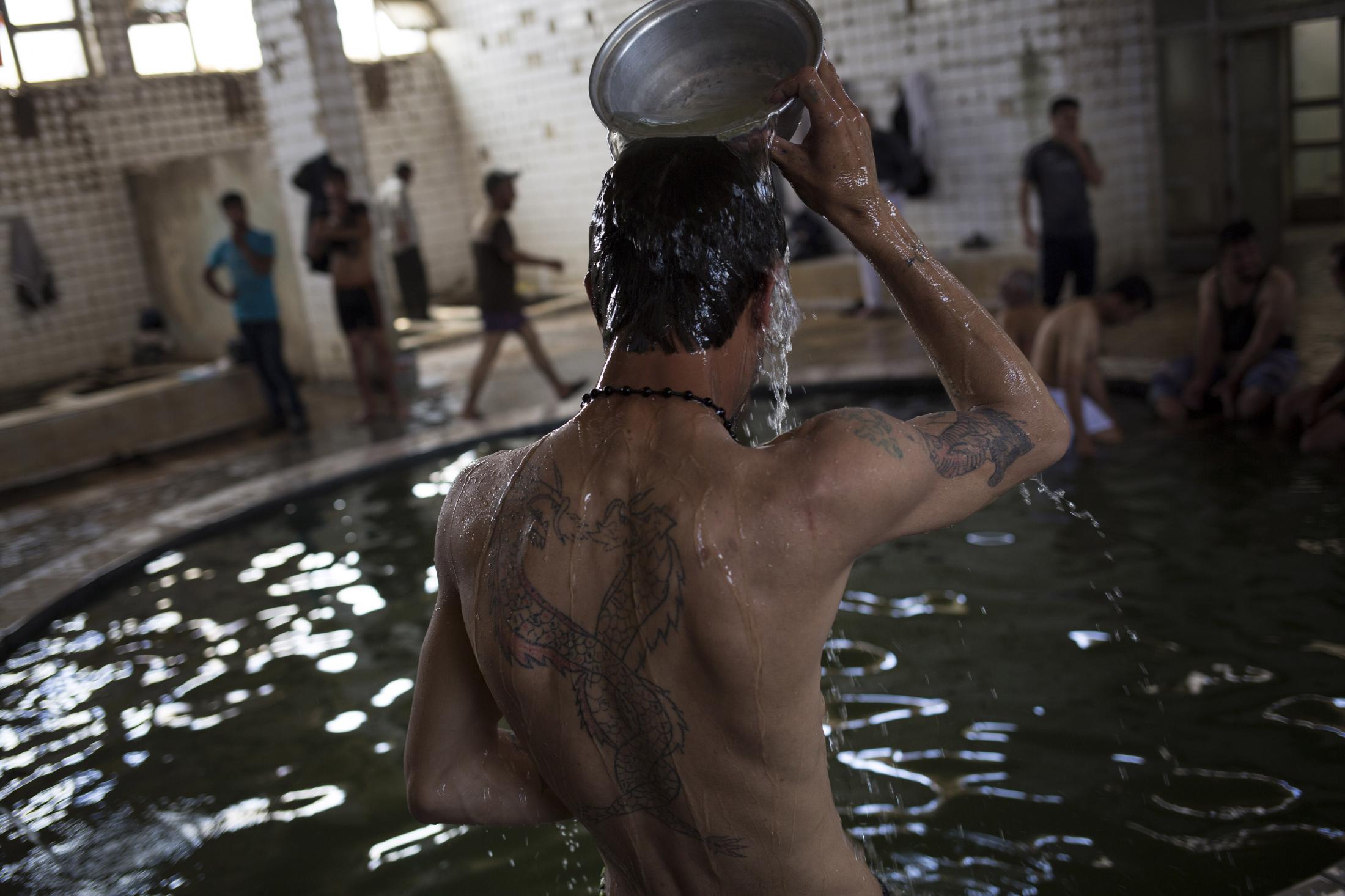 A customer pours water over himself in the Hamam Alil sulphur spa south of Mosul, Iraq, on Thursday, April 27, 2017. Many Iraqi soldiers go to the...