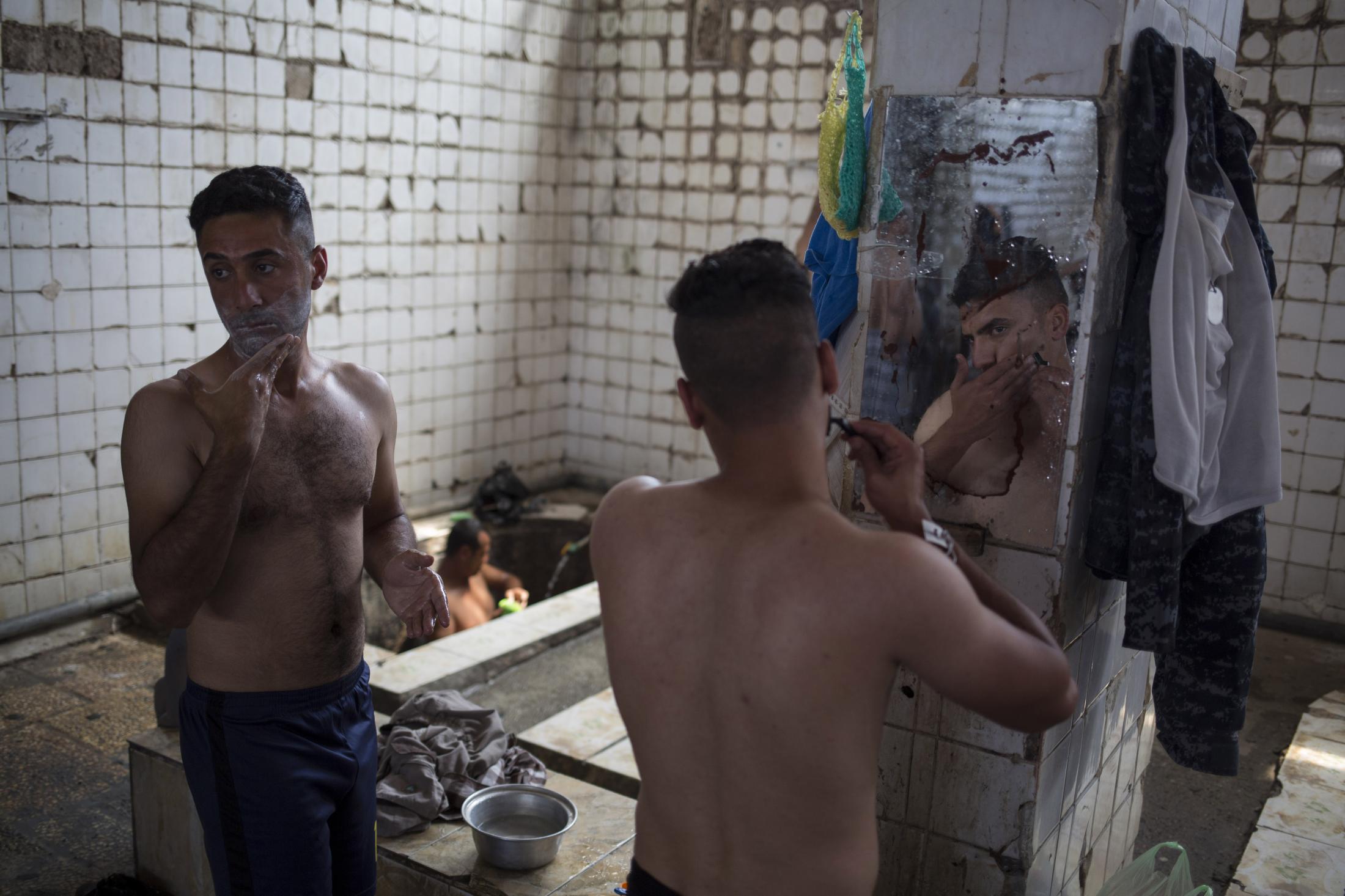 A Spa in Wartime - A customer shaves in front of a mirror in the Hamam Alil...