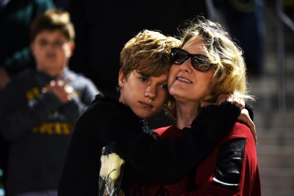 Jack Ewers, 13, leans on his mother Tam Ewers during a prayer before Rock Bridge High School plays at Helias Catholic High School on Friday, Oct. 19, in Jefferson City Friday. They came to see his brother play in the band for senior night.