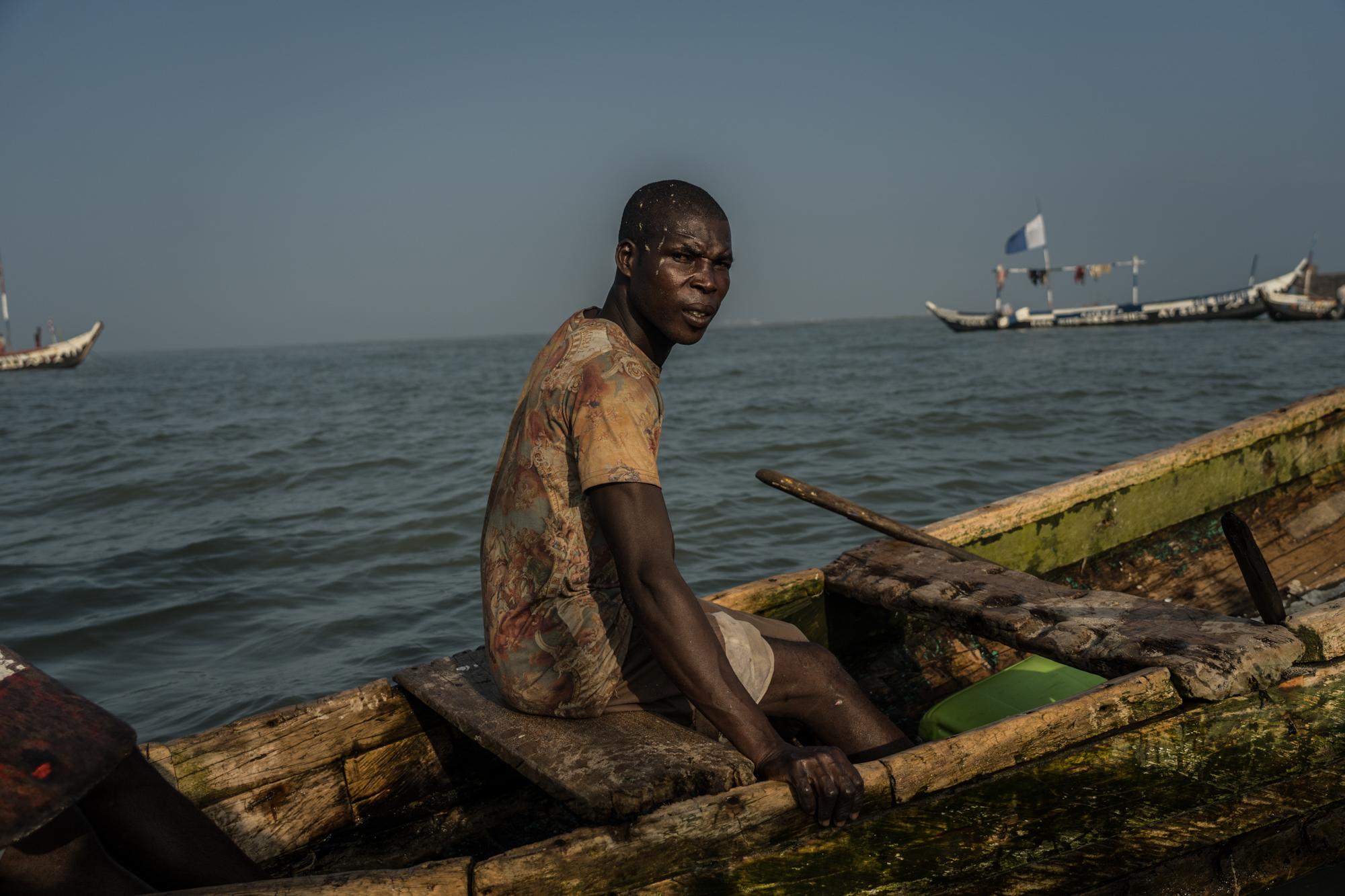 Eric Quaye Ade, a Ghanaian fisherman, sits in his boat in the waters at the Gulf of Guinea where he has been working for almost 20 years.