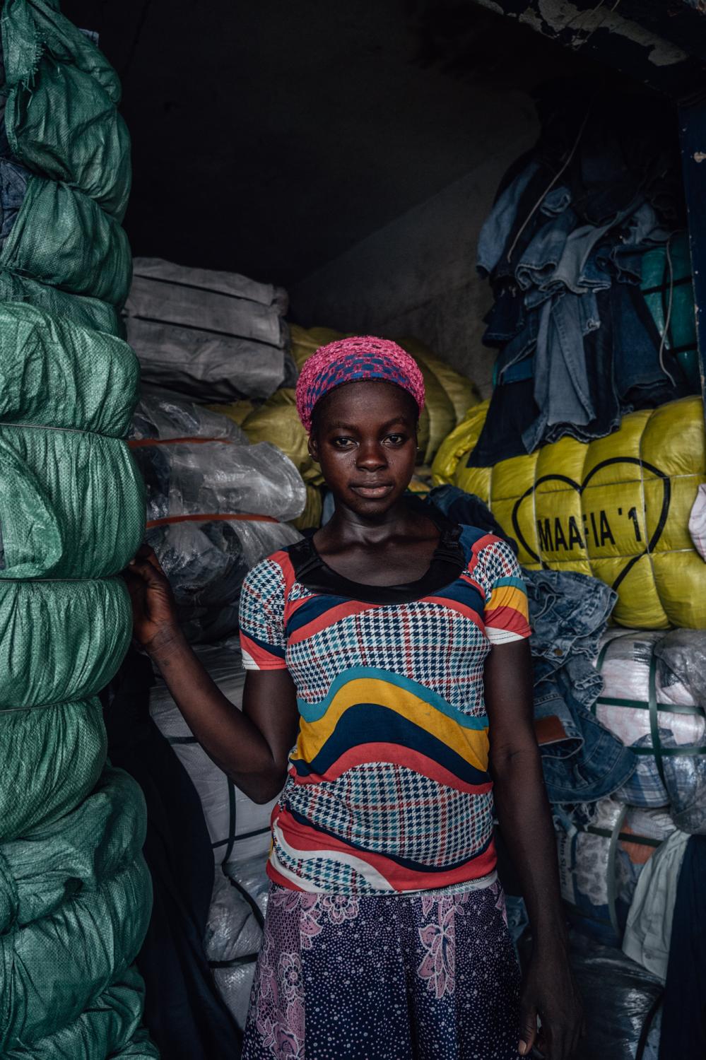 Kayayei Sisters - Rahina is standing by the clothes bales that weight a...