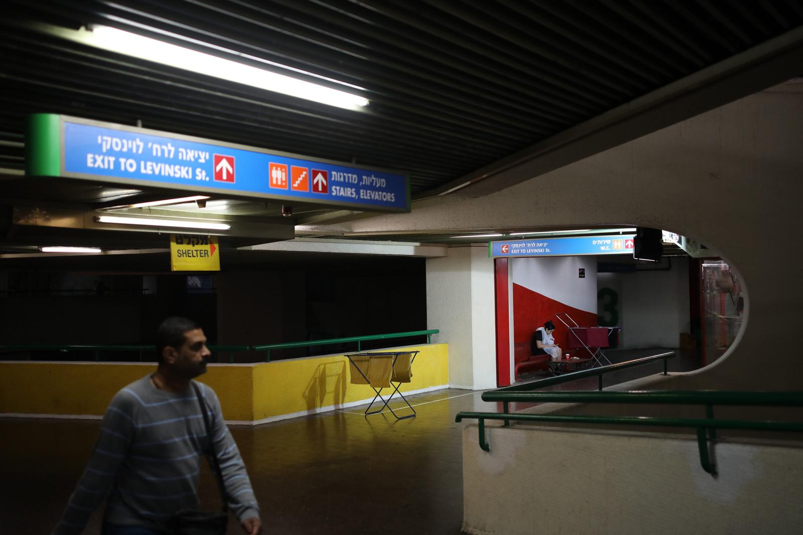 A man walks by as a woman waits outside a hairdresser shop at the Central Bus Station in Tel...