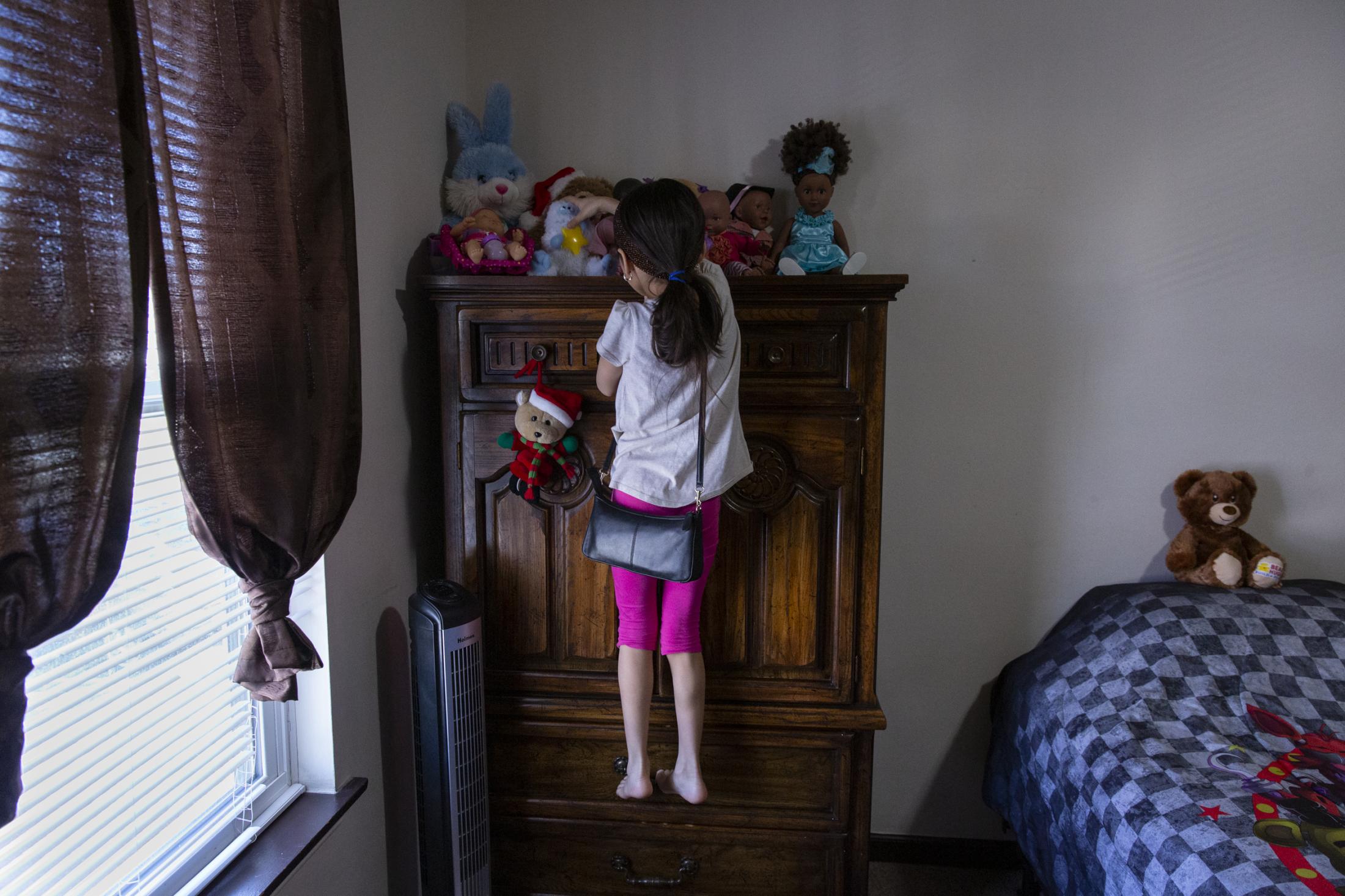 People - Intisar Bakour, 8, reaches for her favorite doll in her...