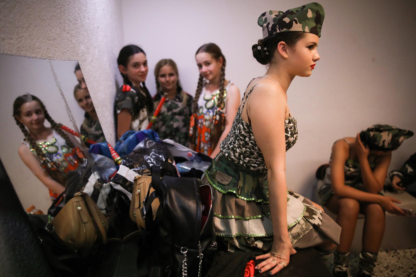 Young women prepare backstage for a performance during an event in remembrance of Victory Day,...