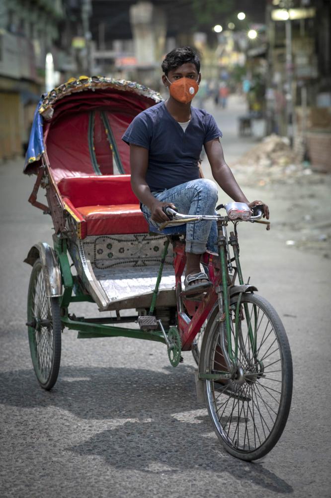 Khokon (20) poses for a picture...th rickshaw to feed his family.