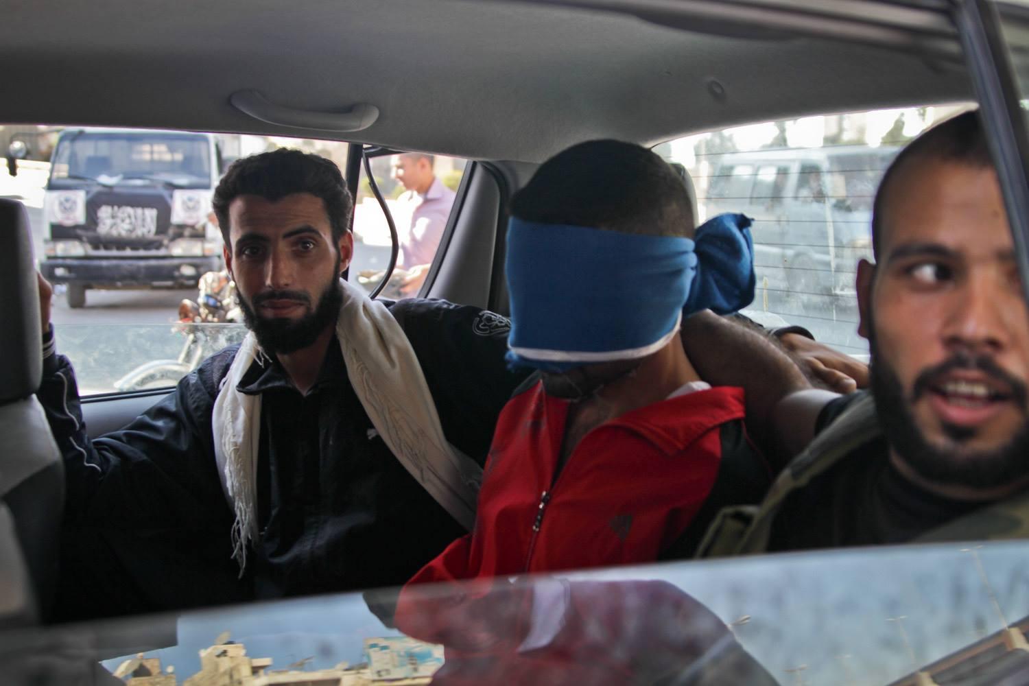 Near the Free Syrian Army makeshift headquarters, FSA fighters drive through a neighborhood in Aleppo with a member of what they believe to be part of the Shabiha on August 21, 2012. Rebels surrounded the car chanting &quot;allahu akbar&quot; (meaning god is great). The man blindfolded was taken to an undisclosed location.