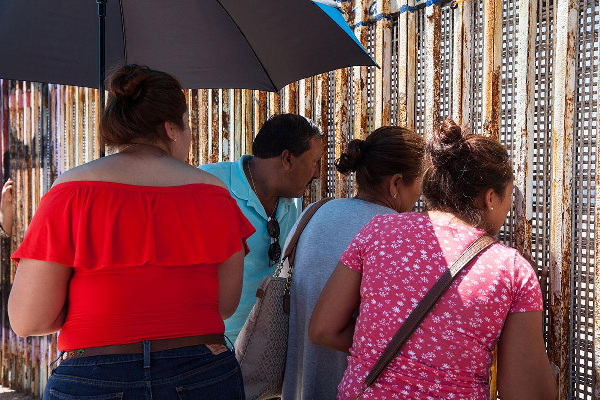 A family at the border fence at Playas de Tijuana, Mexico. A family visits their relative on the U.S. side and talks to them through an open weave metal fence. On the U.S. side there is only a four hour window to visit family members who live in Mexico. There are no restrictions on the Mexican side.