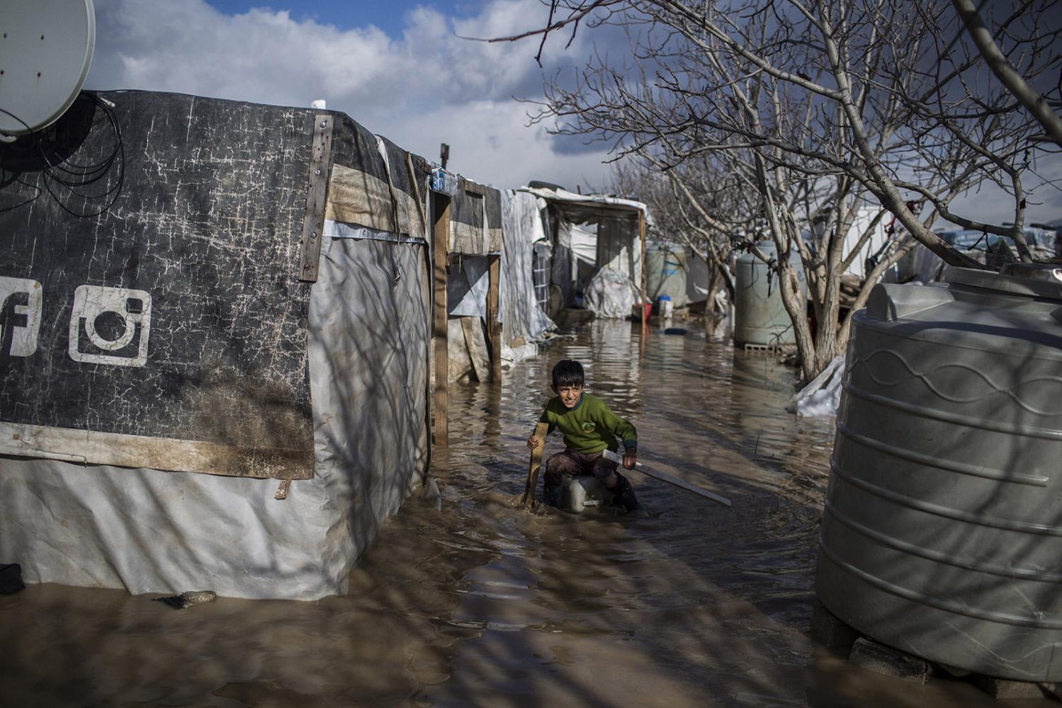 Storm - A young Syrian refugee plays at the flooded streets of...