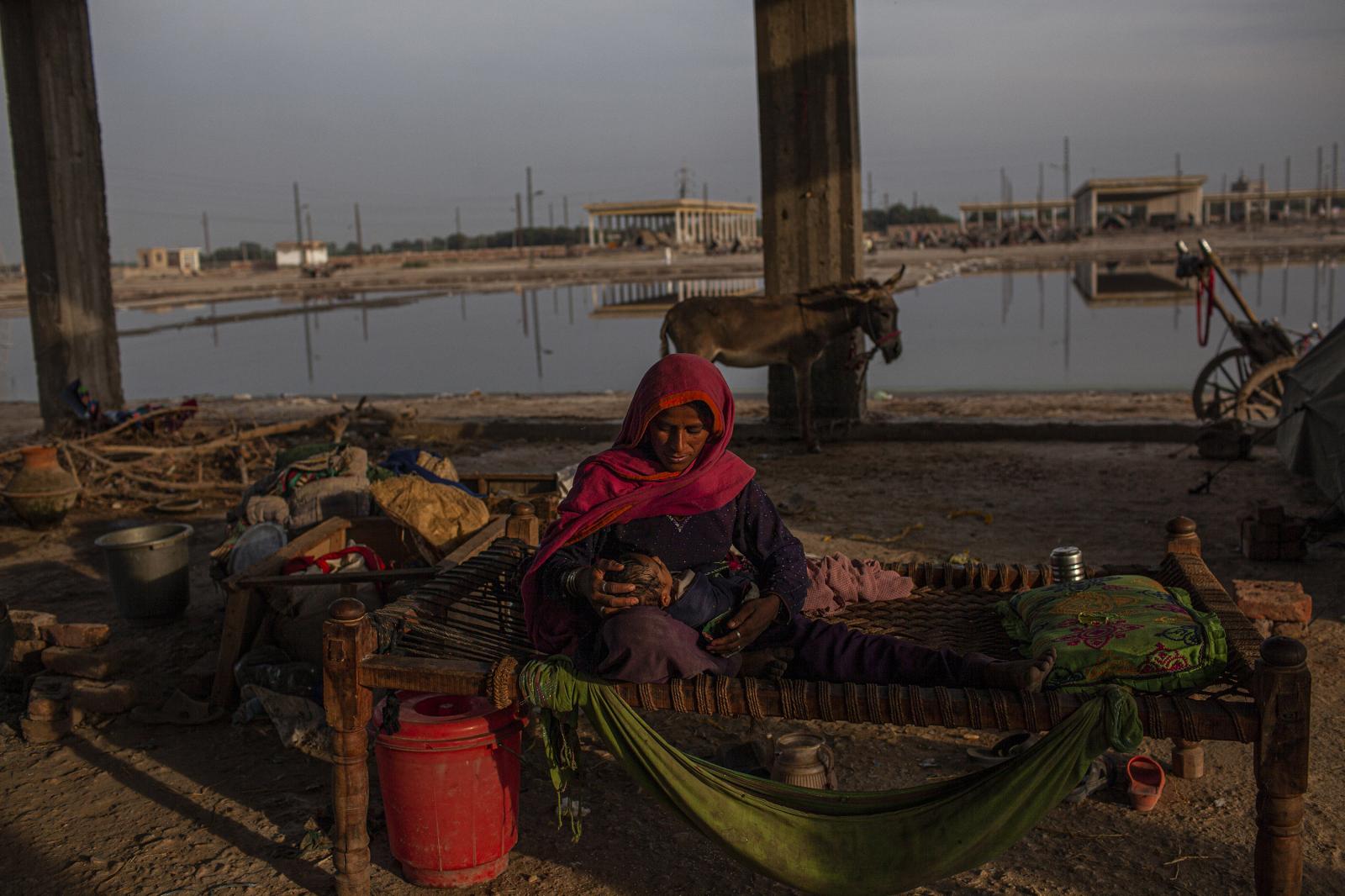 Floods - An Pakistani IDP warms her baby in the morning inside a...