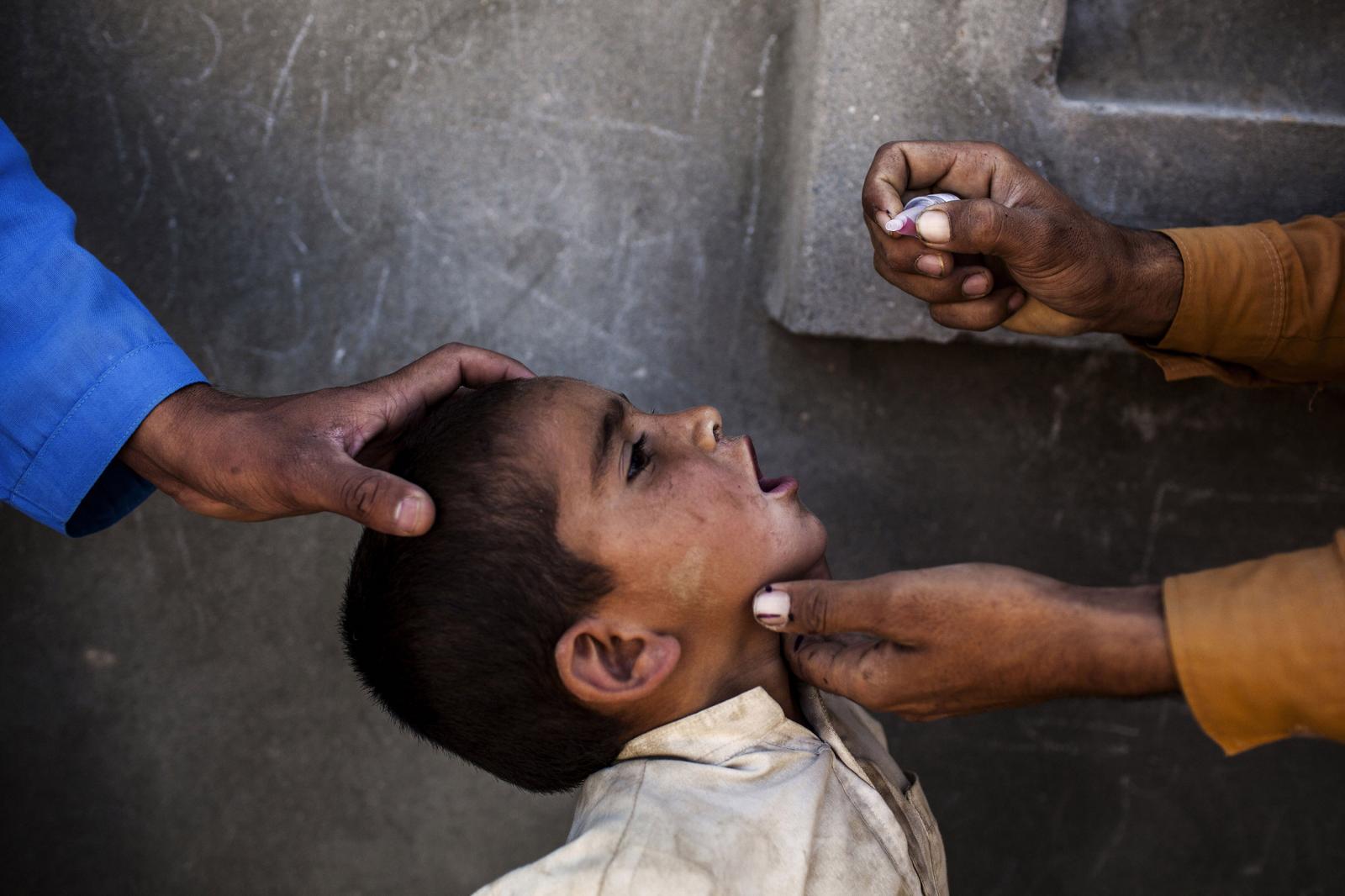 War on Polio - Health workers vaccinate a child in Afghanistan during...