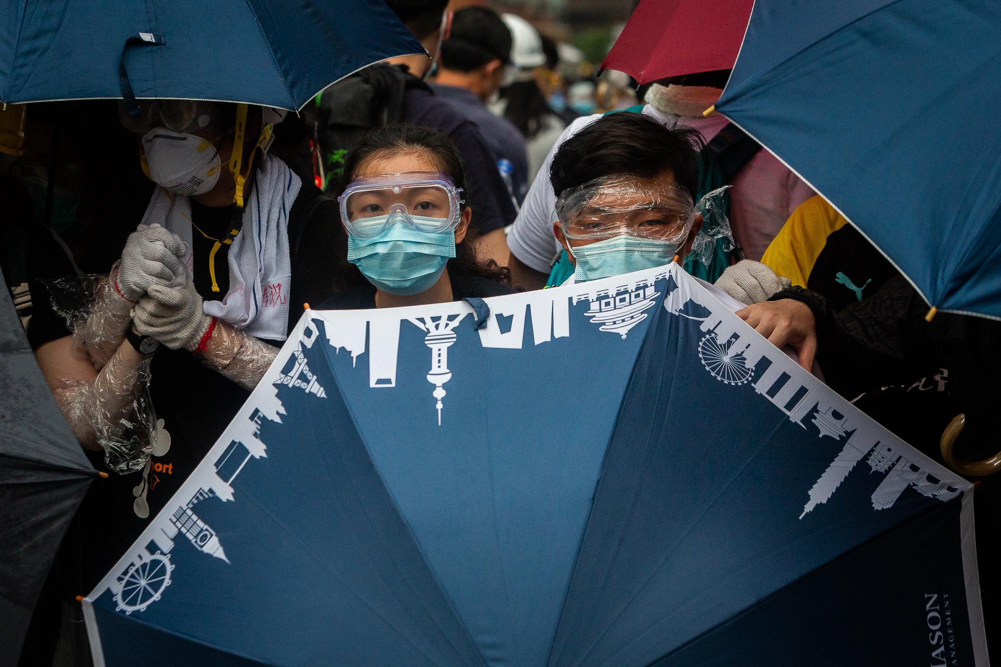Demonstrators protect themselves behind an umbrella during a protest against a proposed...